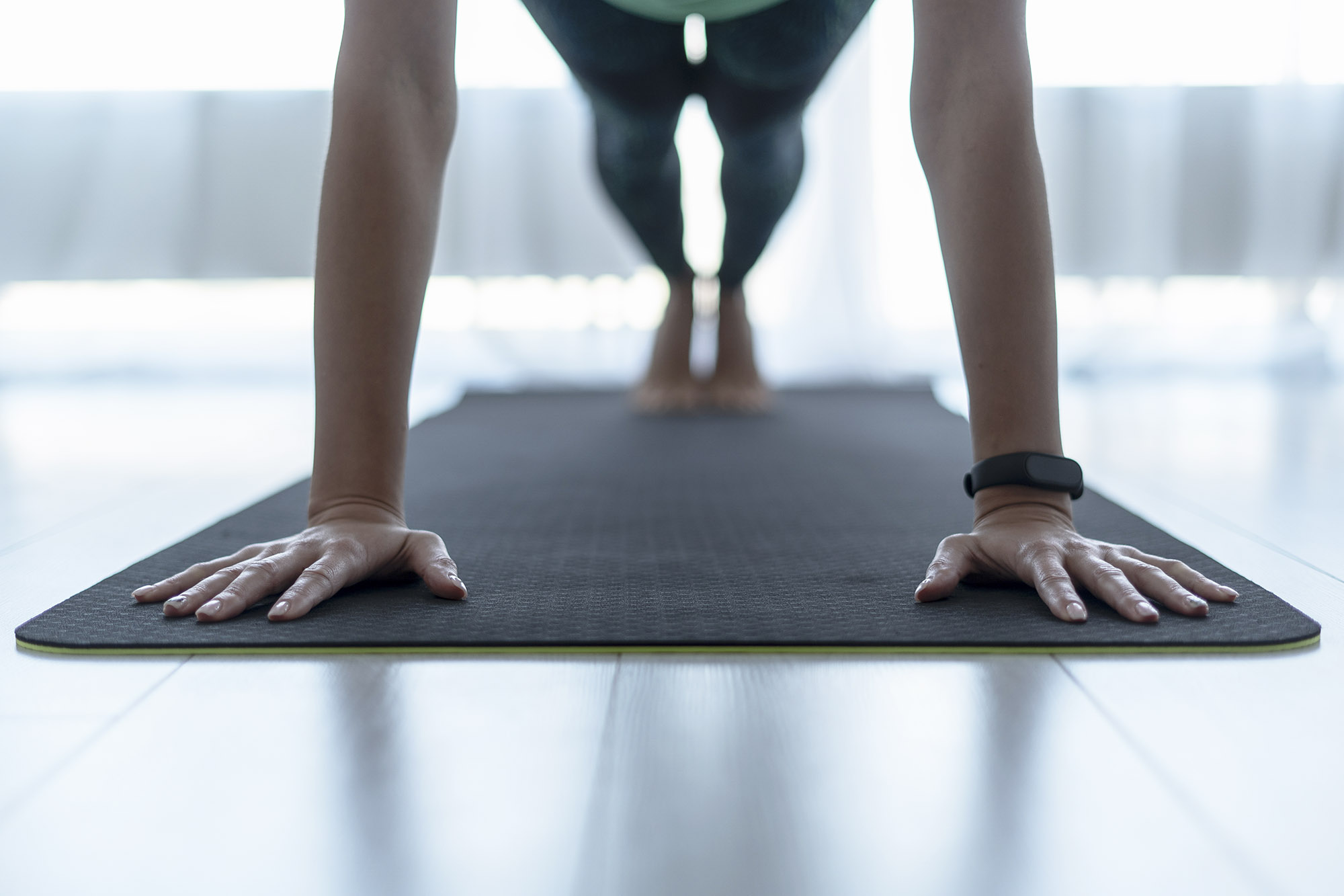 Woman on an exercise mat holding herself up with her arms and legs