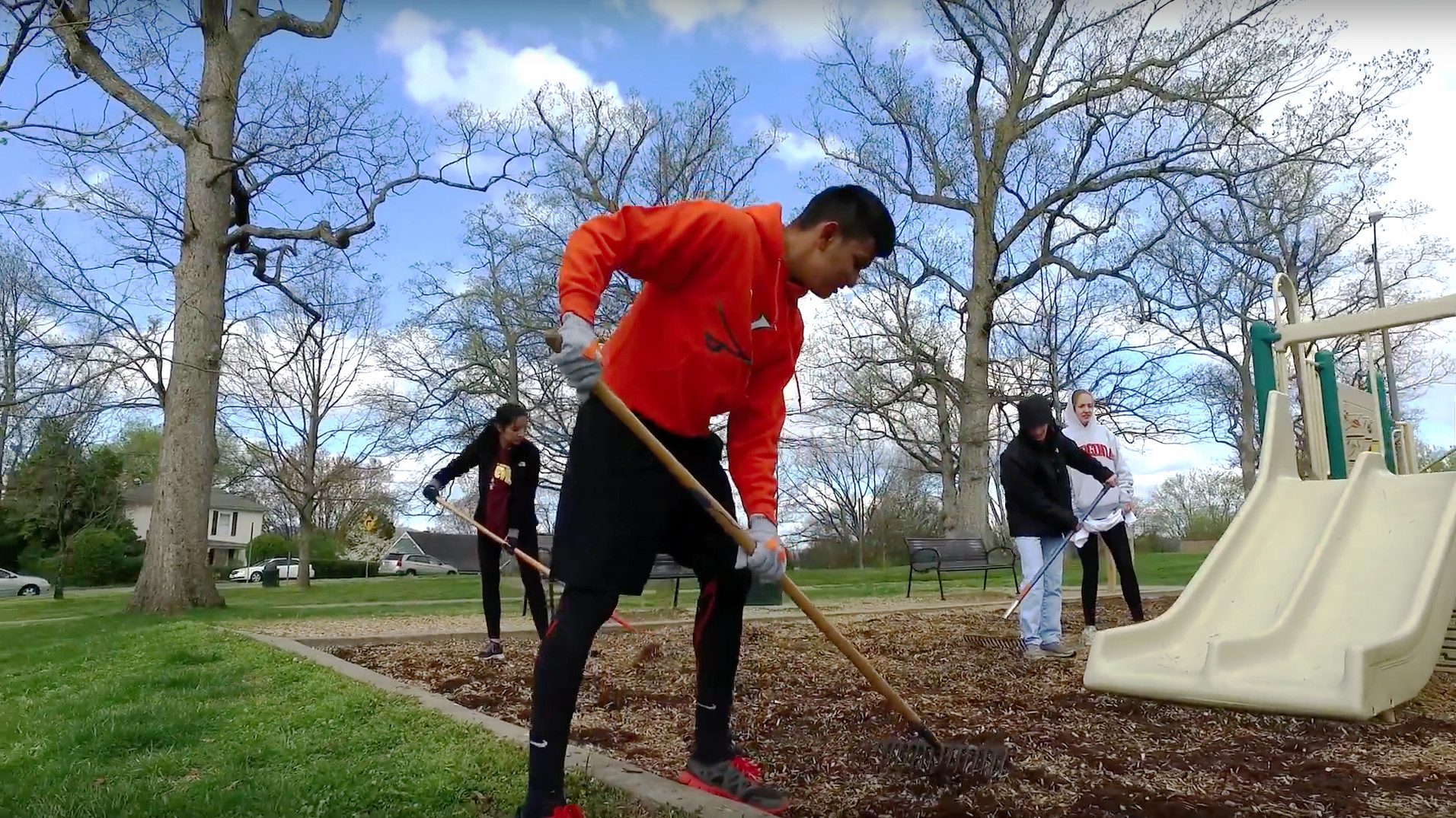 Students raking mulch at a playground