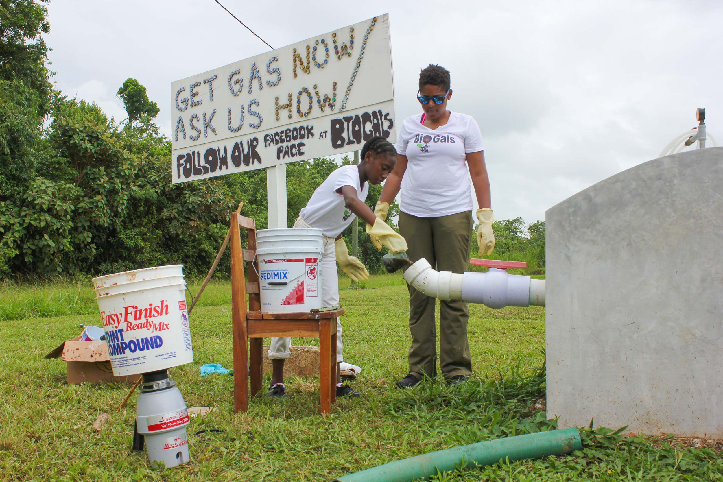 Ashanti Thompson, left, and Evvan Morton, work together to pour a liquid in to a pvc pipe connected to a concrete tube