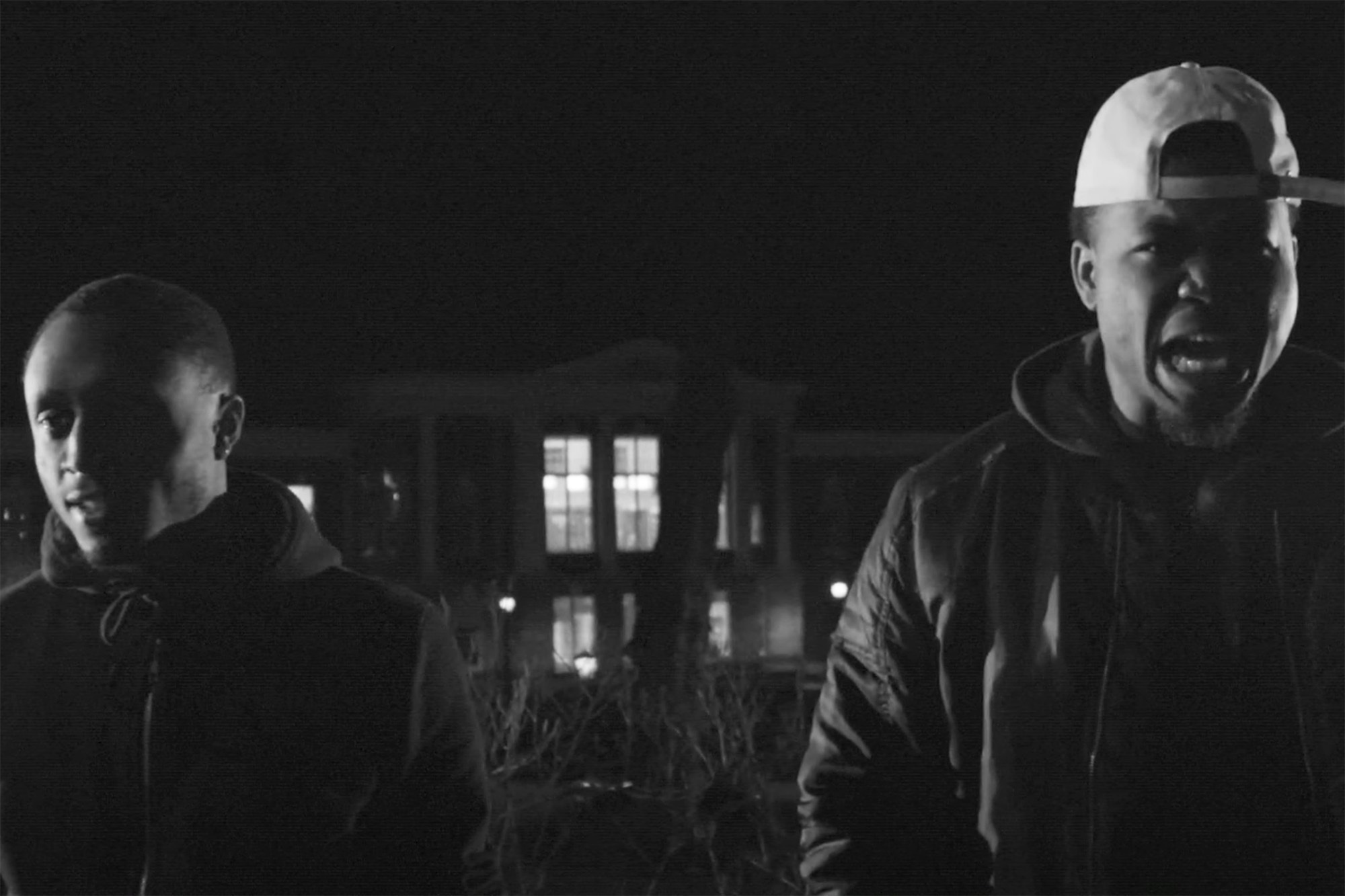 Two African American's standing in front of a building at night.  The man on the right is speaking
