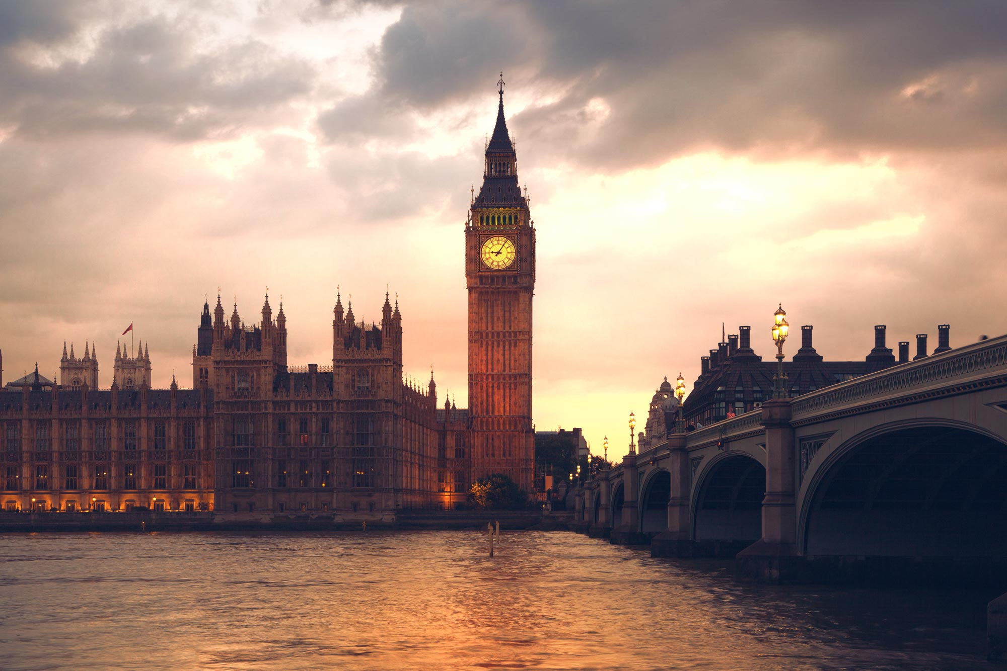 Big ben seen from the river as the sunsets and casts an orange glow upon it