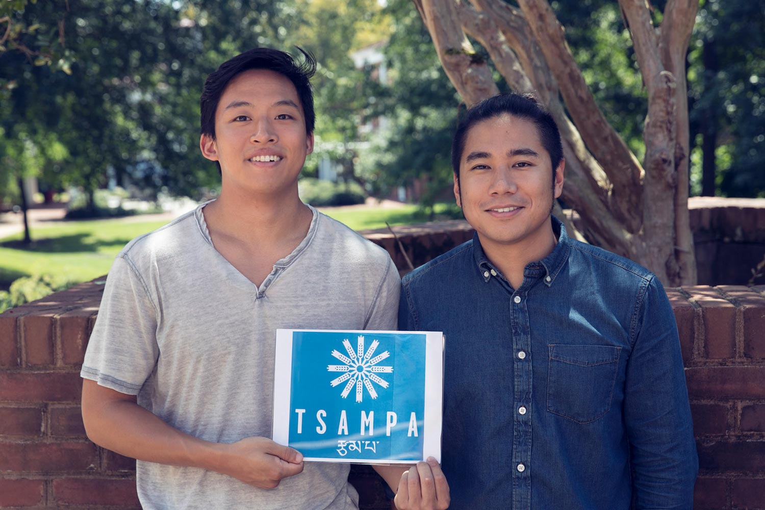 Chenam Barshee and Sogyel Lhungay stand together holding a piece of paper together that reads TSAMPA