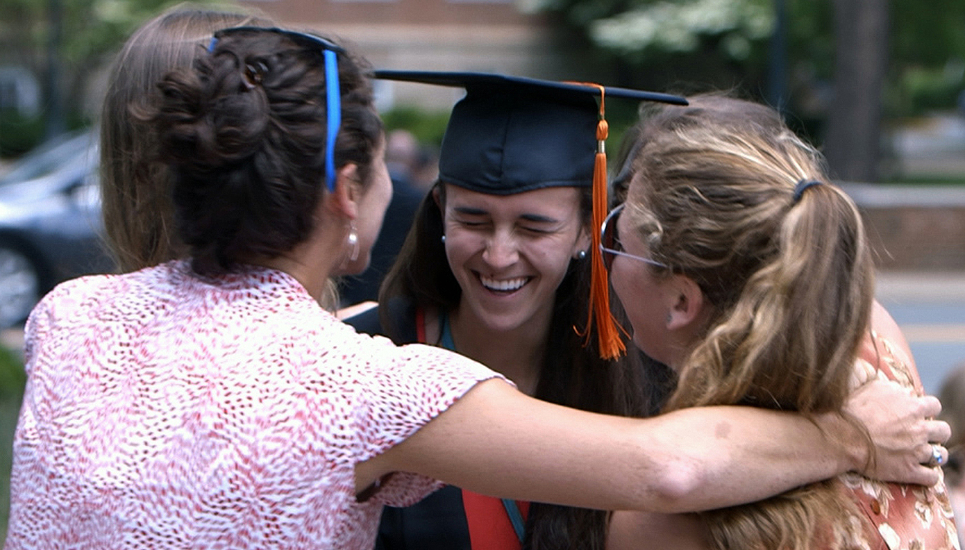 Graduate embracing her friends