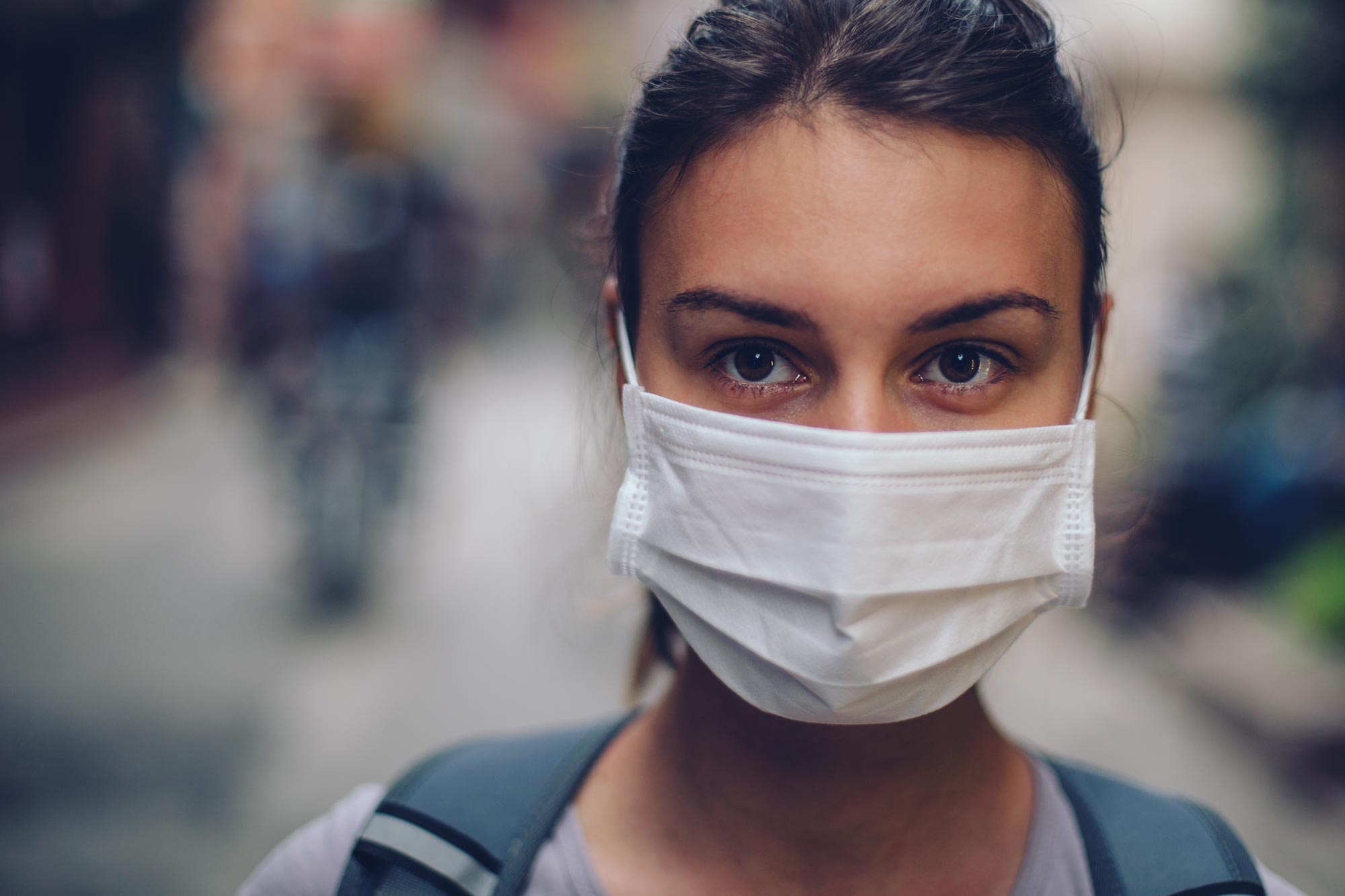 Woman wearing a white mask looking into the camera