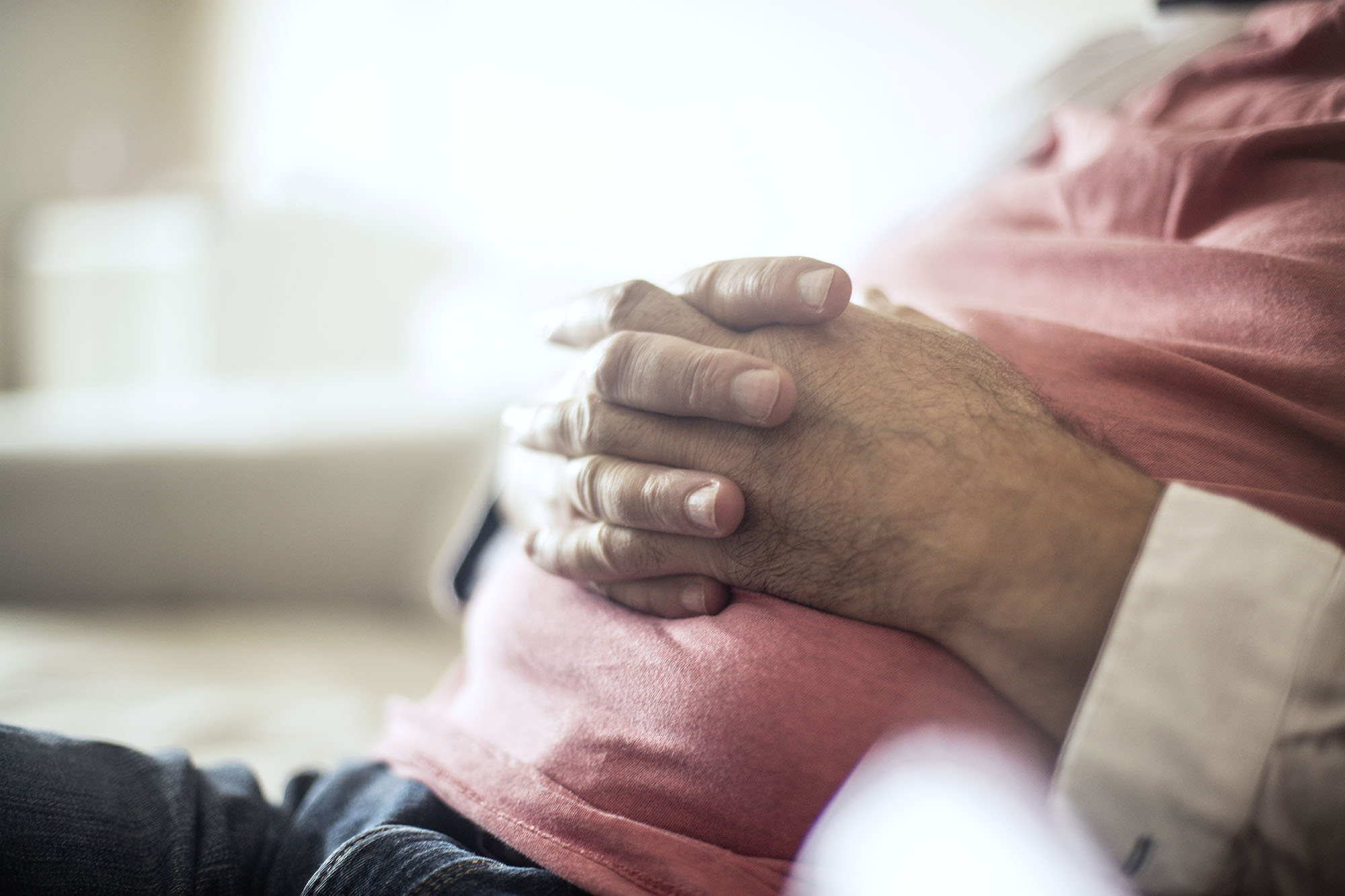 Man sitting with his hands interlocked on their stomach