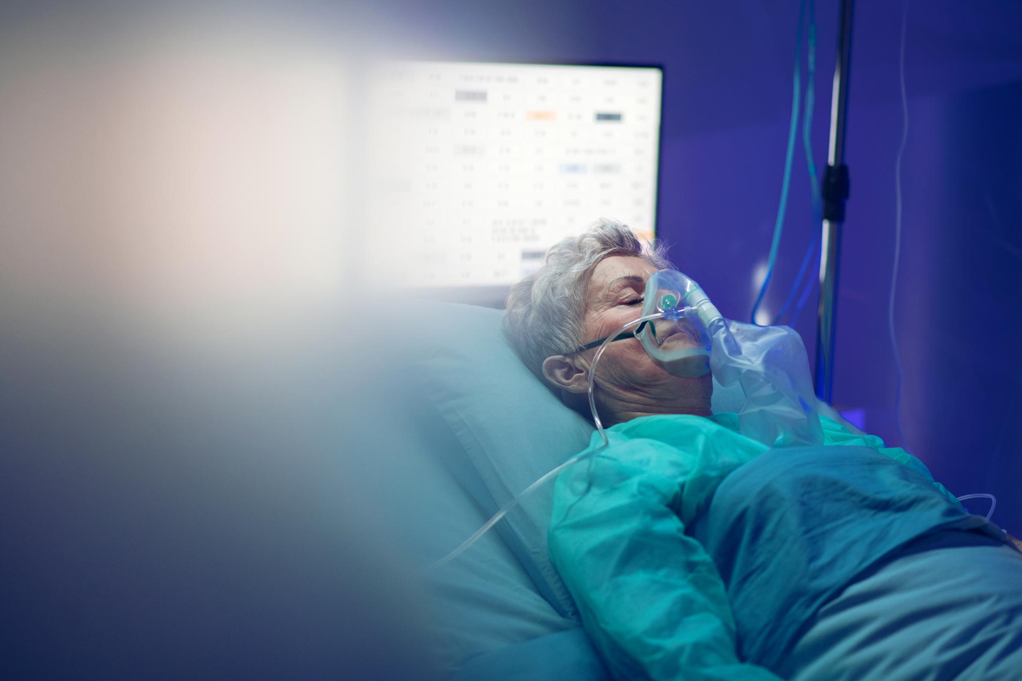 Woman laying in hospital bed with oxygen mask