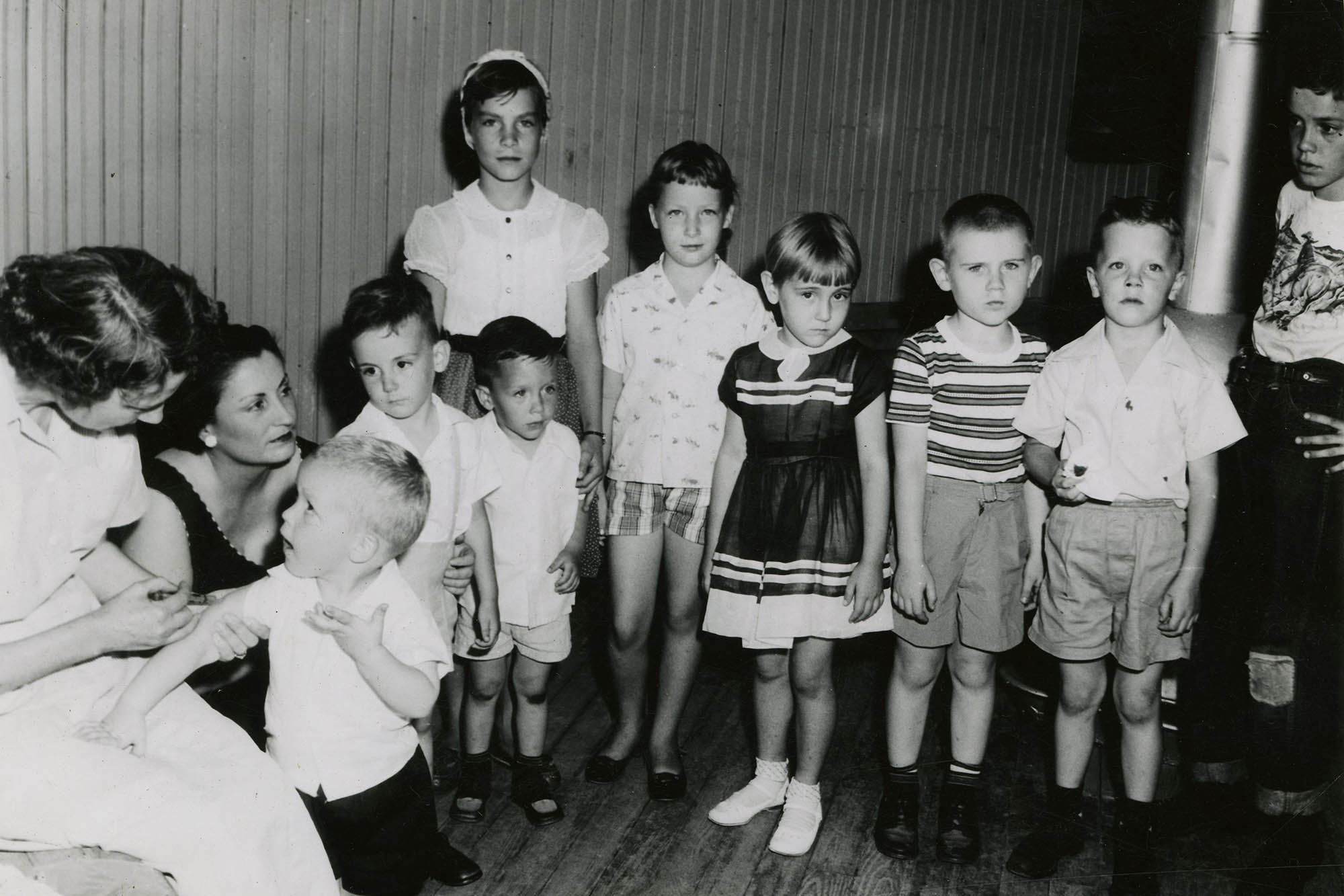 Black and White photo of children waiting to get their polio vaccine in 1956