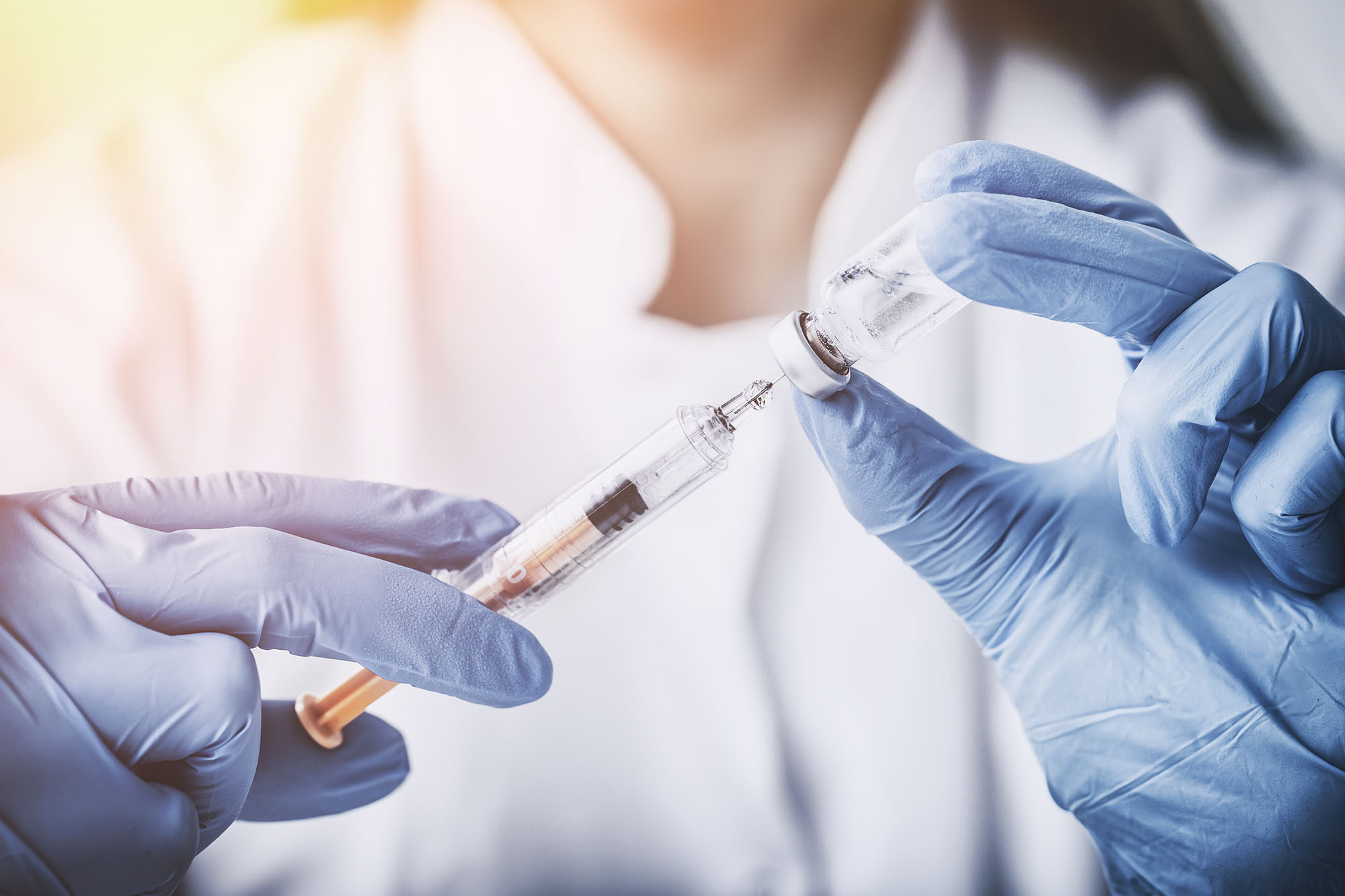 Healthcare professional drawing up a vaccine into a syringe 