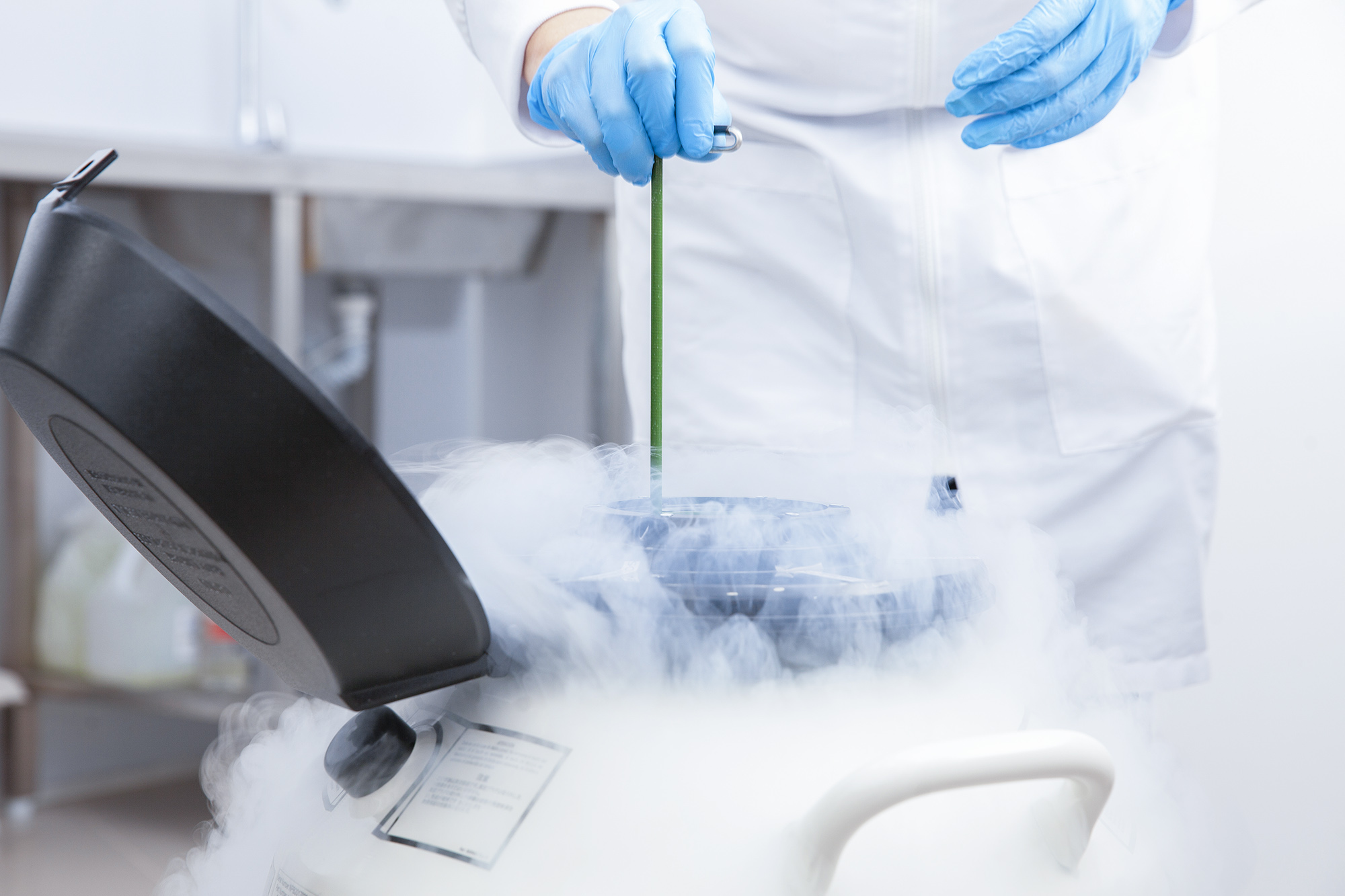 Medical Professional pulling something from a cryogenic tank while smoke comes flowing out