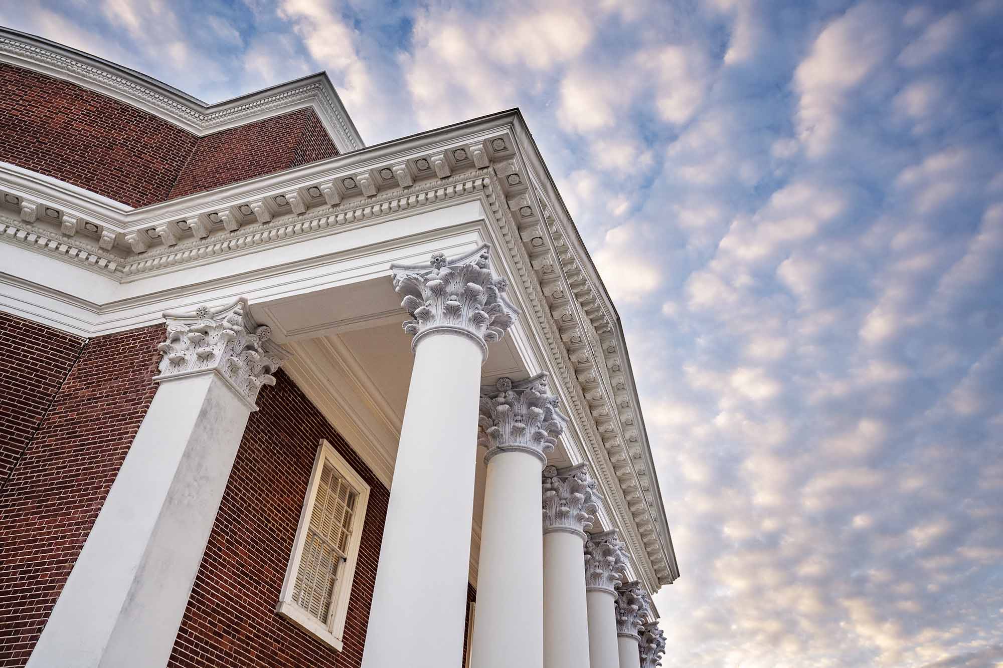 top of the Rotunda columns backgrounded by white clouds on a blue sky