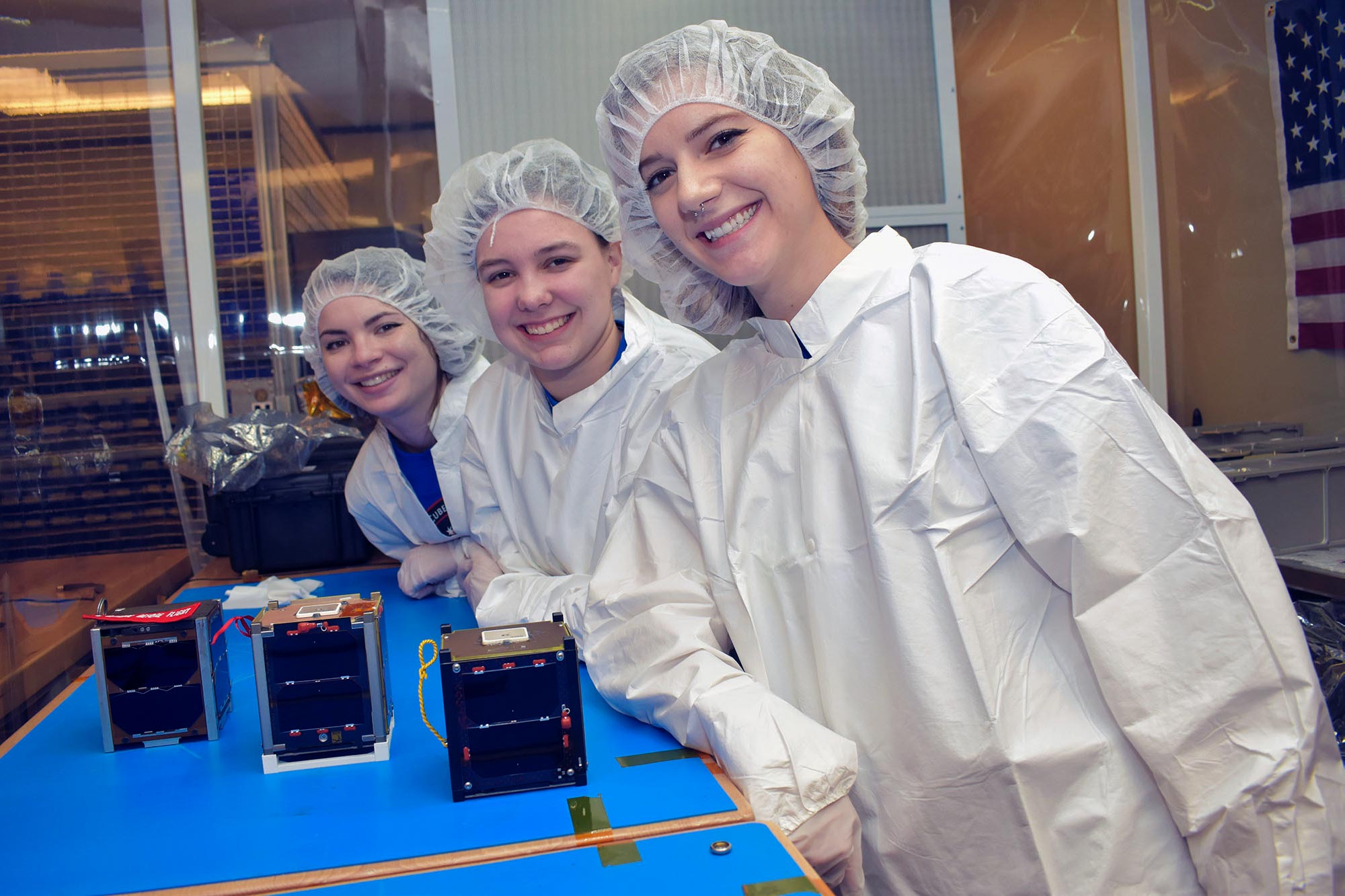 Erin Puckette, center, stands with two others at a table with full lab coats and hair nets