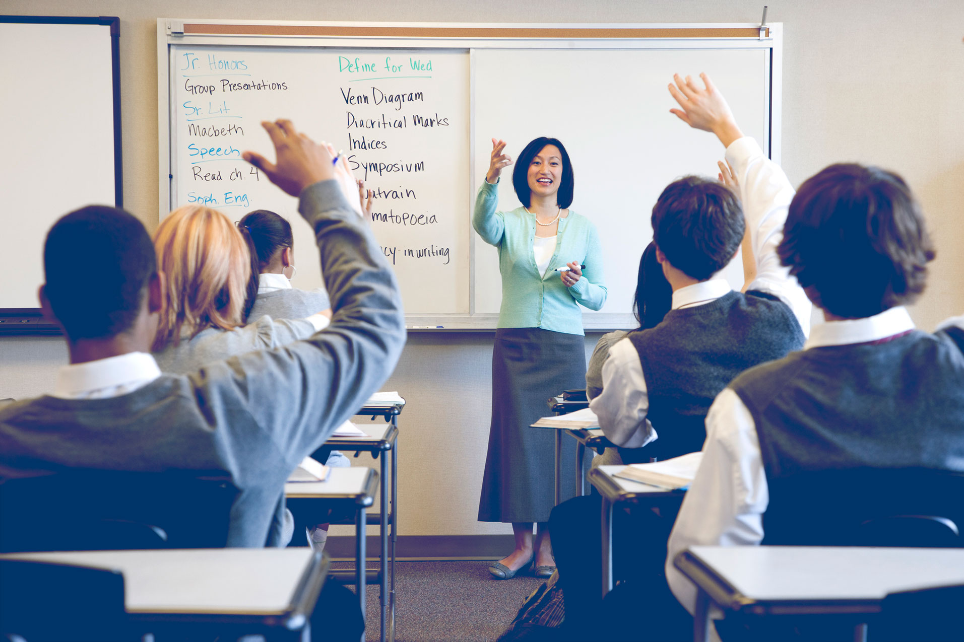 Teacher talking to students who are raising their hands