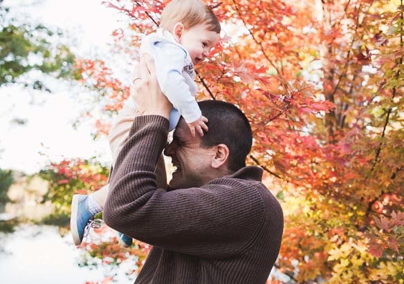 Man holding a toddler up in the air