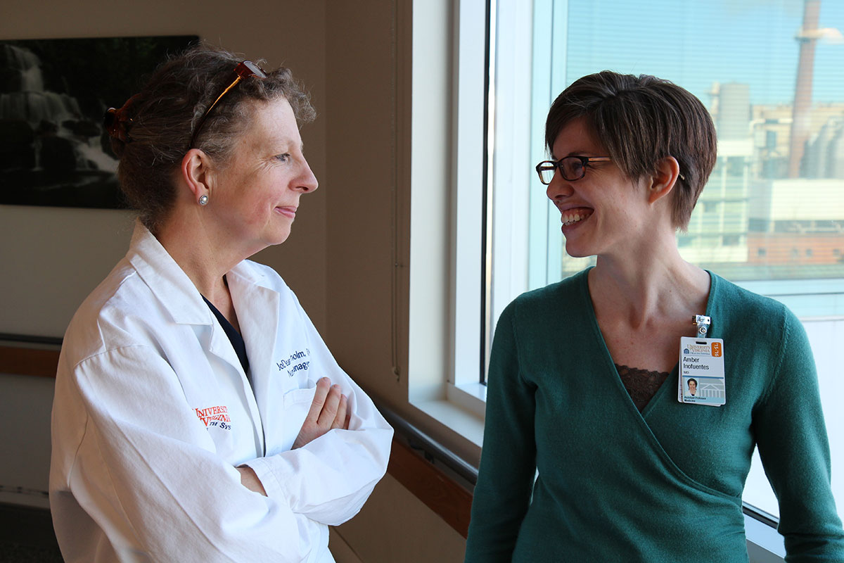 JoDean Chisholm, left, and Dr. Amber Inofuentes talk at a window in the hospital