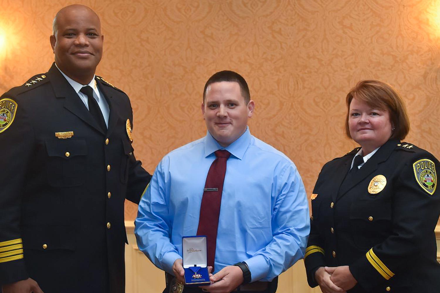 Officer Dean Dotts, center, holds a Medal her won for saving someones life while Chief Tommye Sutton, left, and Deputy Chief Melissa Fielding stand next to him