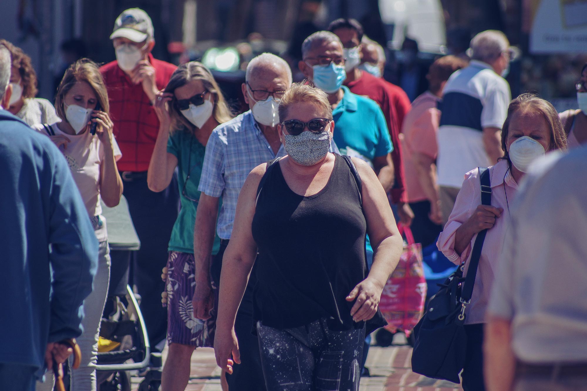 People walking on sidewalks wearing masks