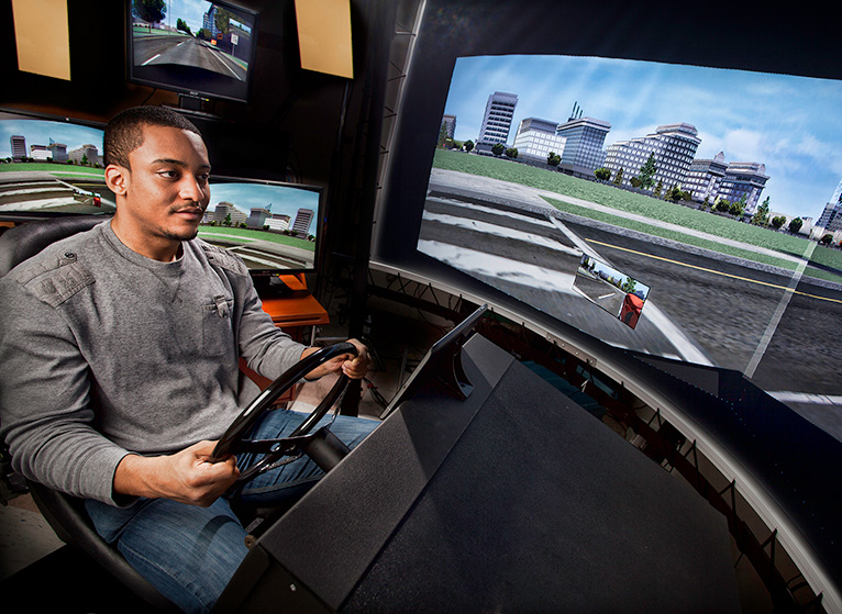 Man sits in a simulated car drivin