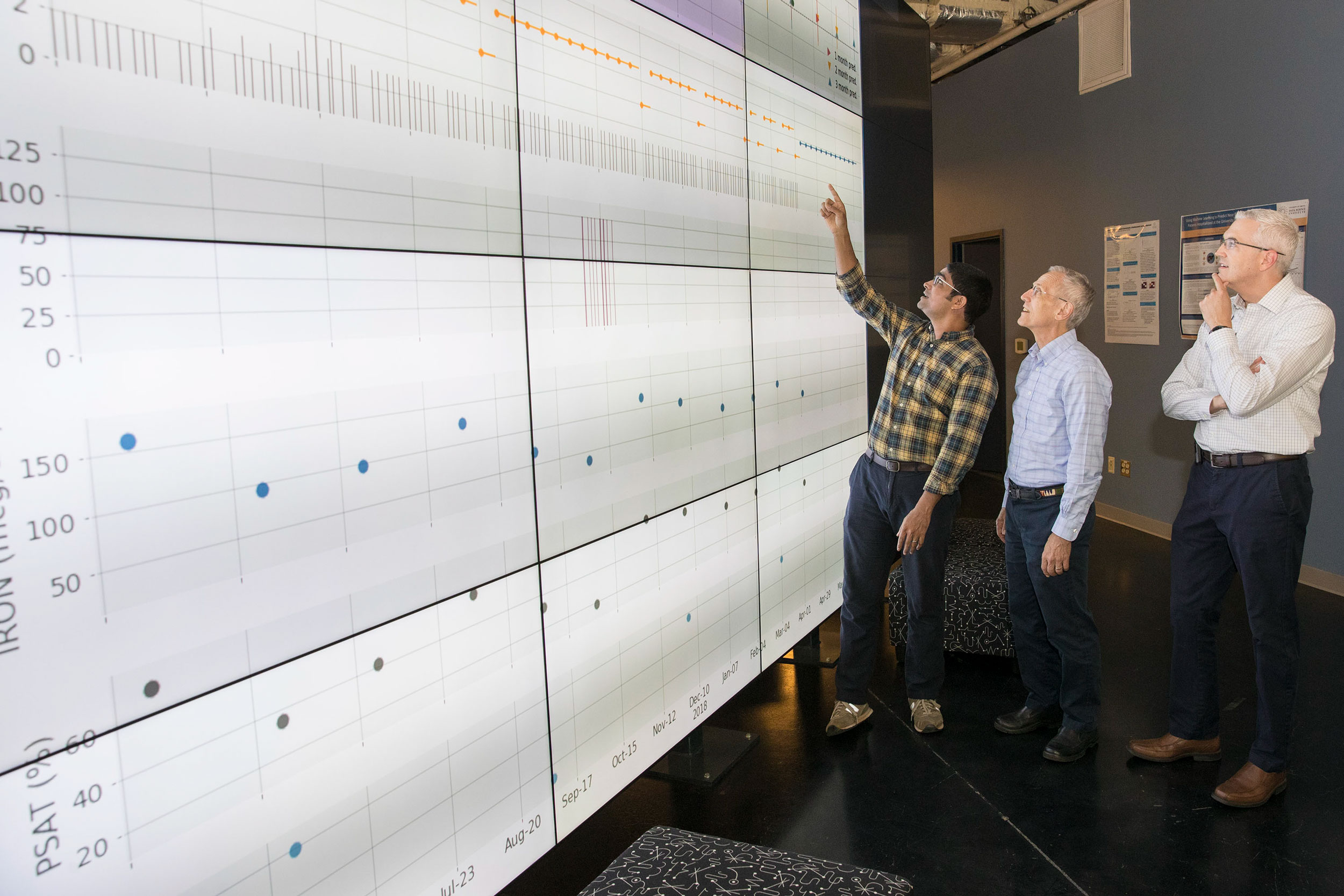 Data scientists Benjamin Lobo, left, and Don Brown, center,  Dr. Brendan Bowman, right look at data on a digital wall