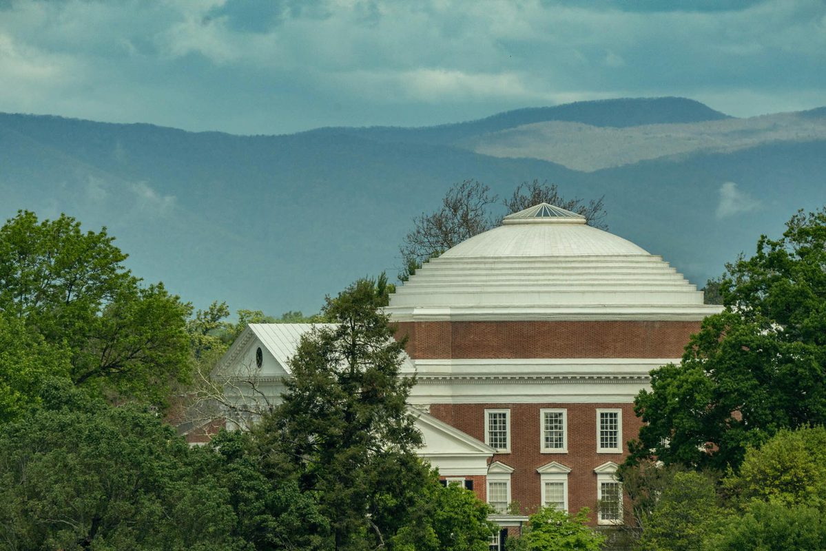 Rotunda against the blue ridge mountains and surrounded by green trees