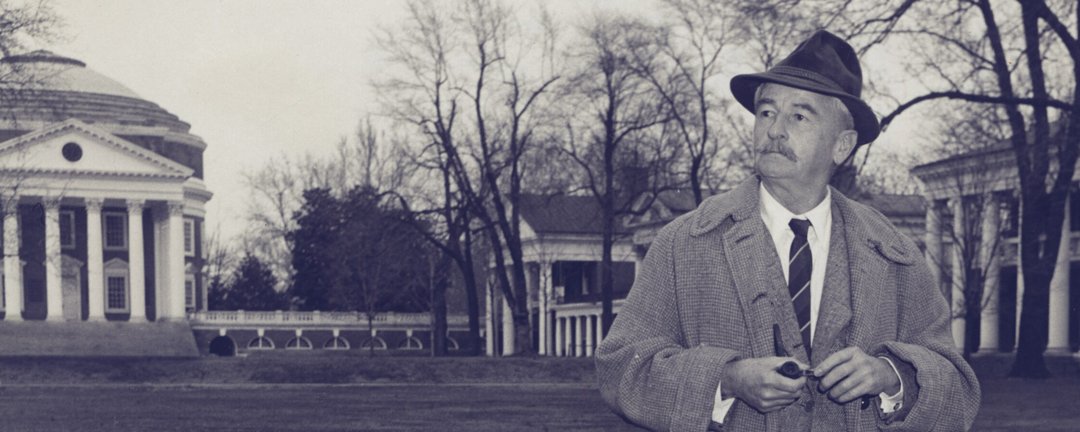 Faulkner standing on the lawn with a pipe. black and white image