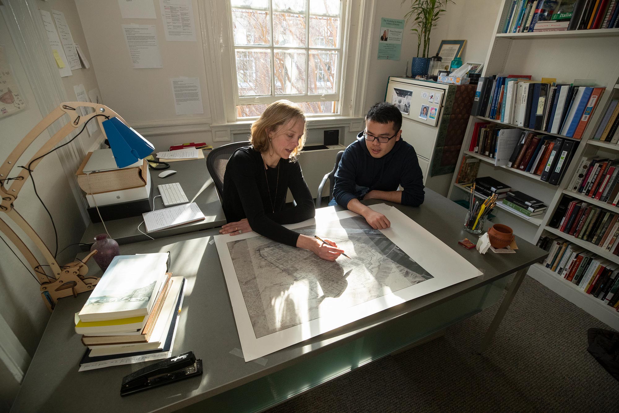 Fiona Greenland, left, works with  Di Shao, right, at a table looking at a map