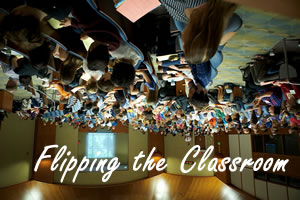 Students in a classroom but the image is upside down with text that reads: Flipping the Classroom