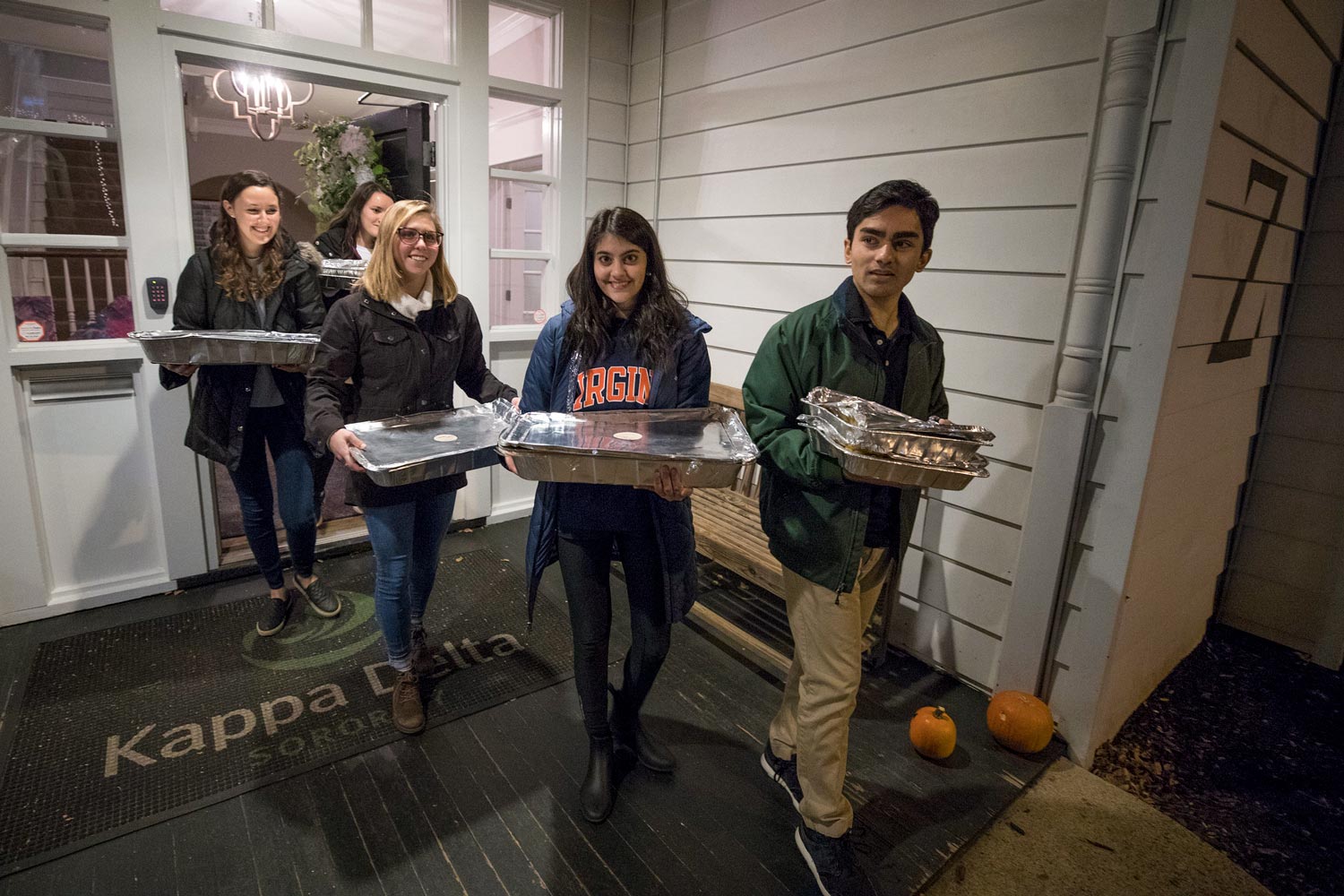 Students Annie Weinberg, Kayla Spigelman, Kristin Blake, Neha Chopra and Anup Nair carry aluminum foil pans out of a house
