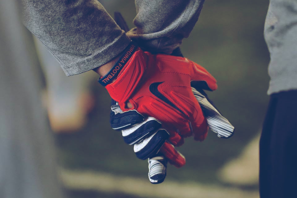 Two people holding hands wearing football gloves