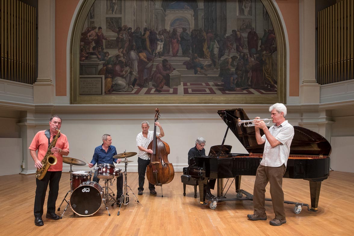 Five men playing jazz instruments in a large room