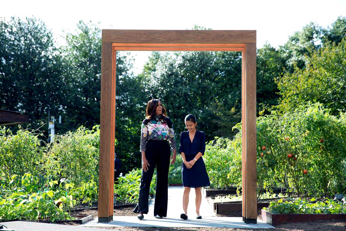 First lady Michelle Obama stands with Tammy Nguyen, standing under an arbor