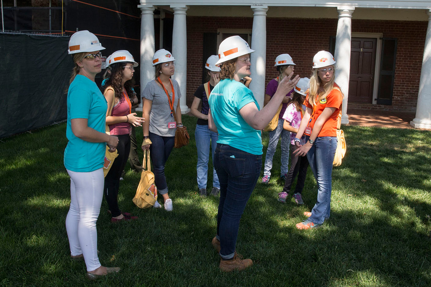 Sarita Herman, center, historic preservation project manager at Facilities Management, takes a group of young women on Grounds for a tour of the renovation work being conducted at Hotel A. 