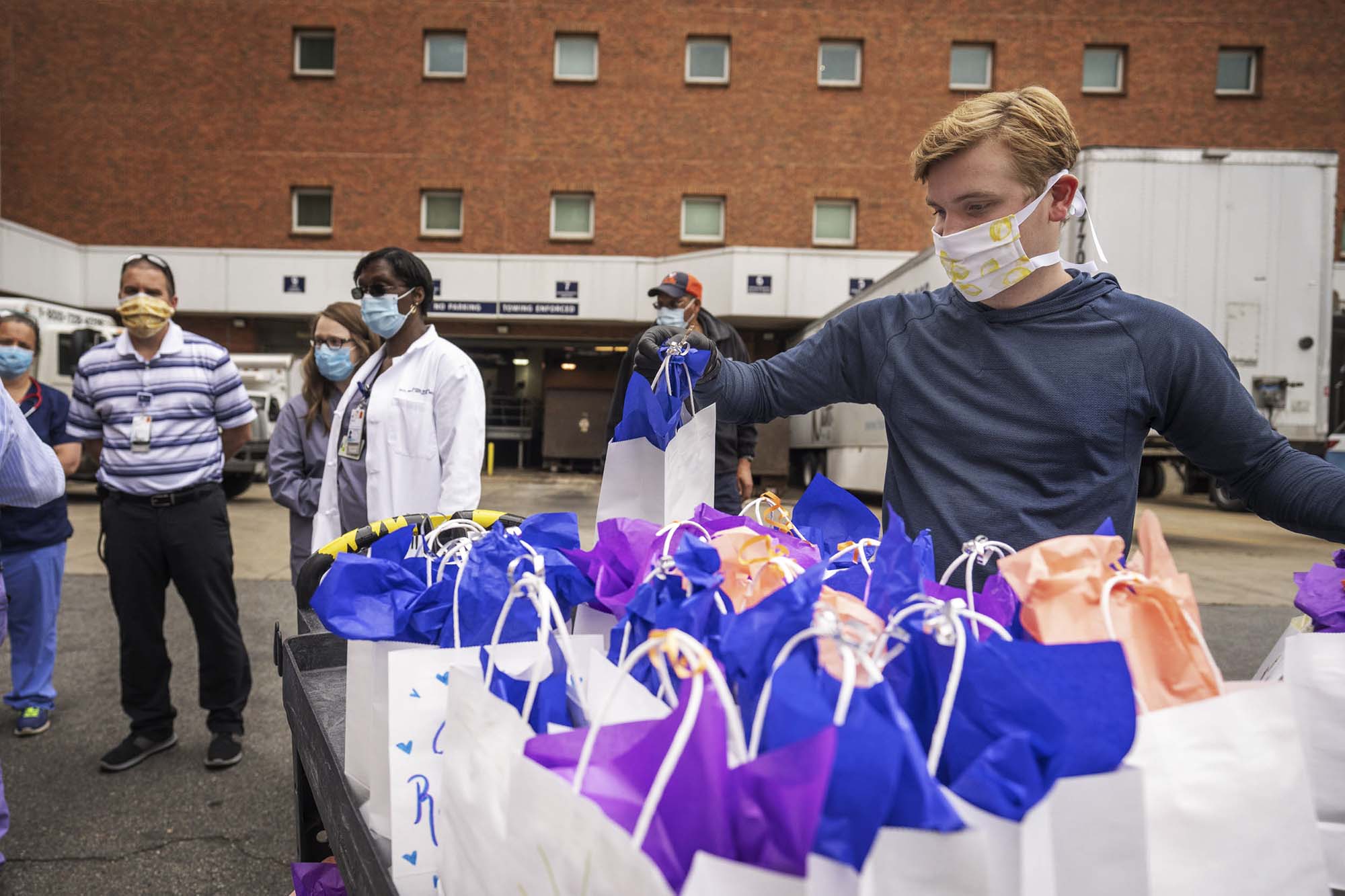 Brett Goerl picking up a white gift bag with blue tissue paper from a table