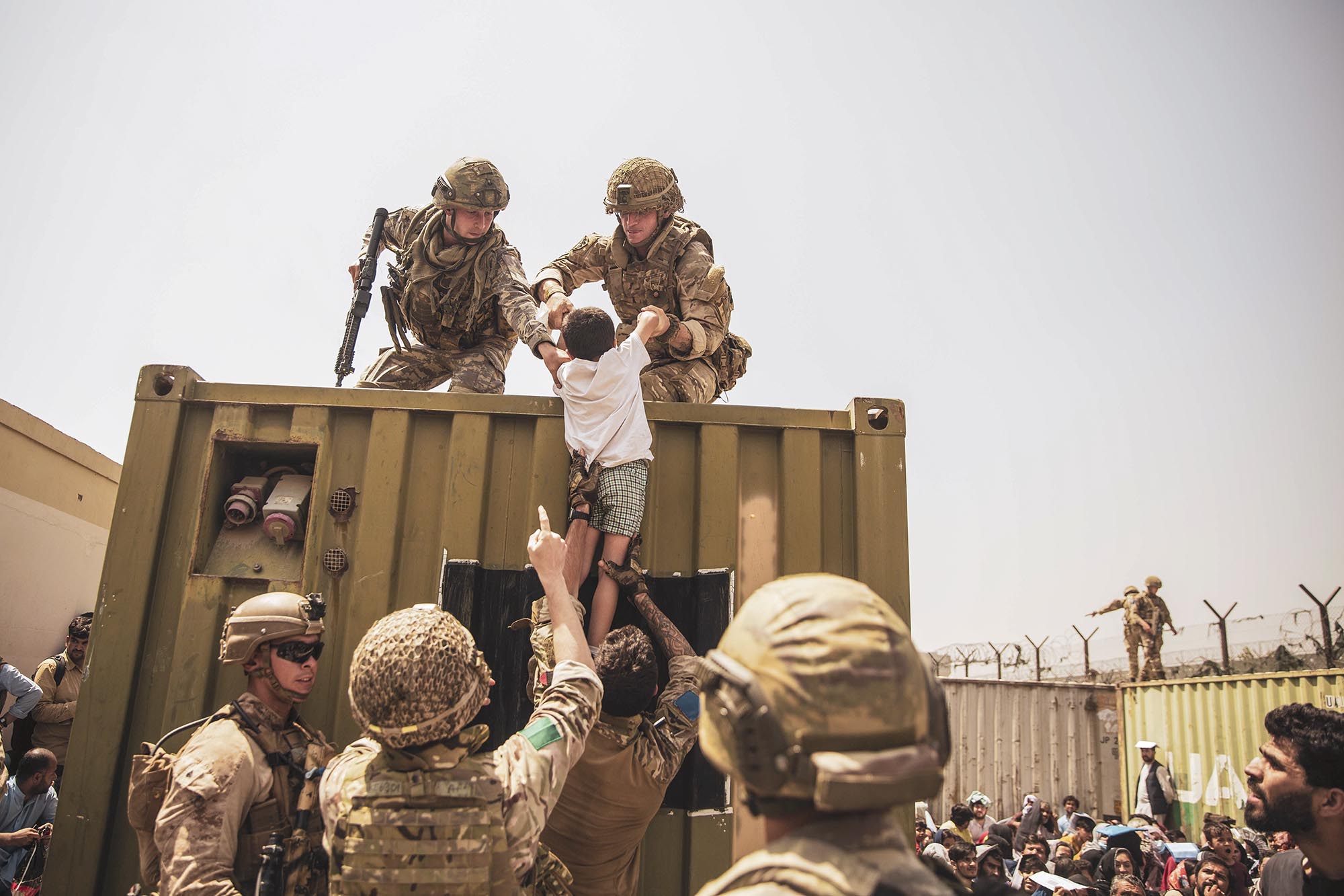 US Marines pull a small child up onto a metal building with them