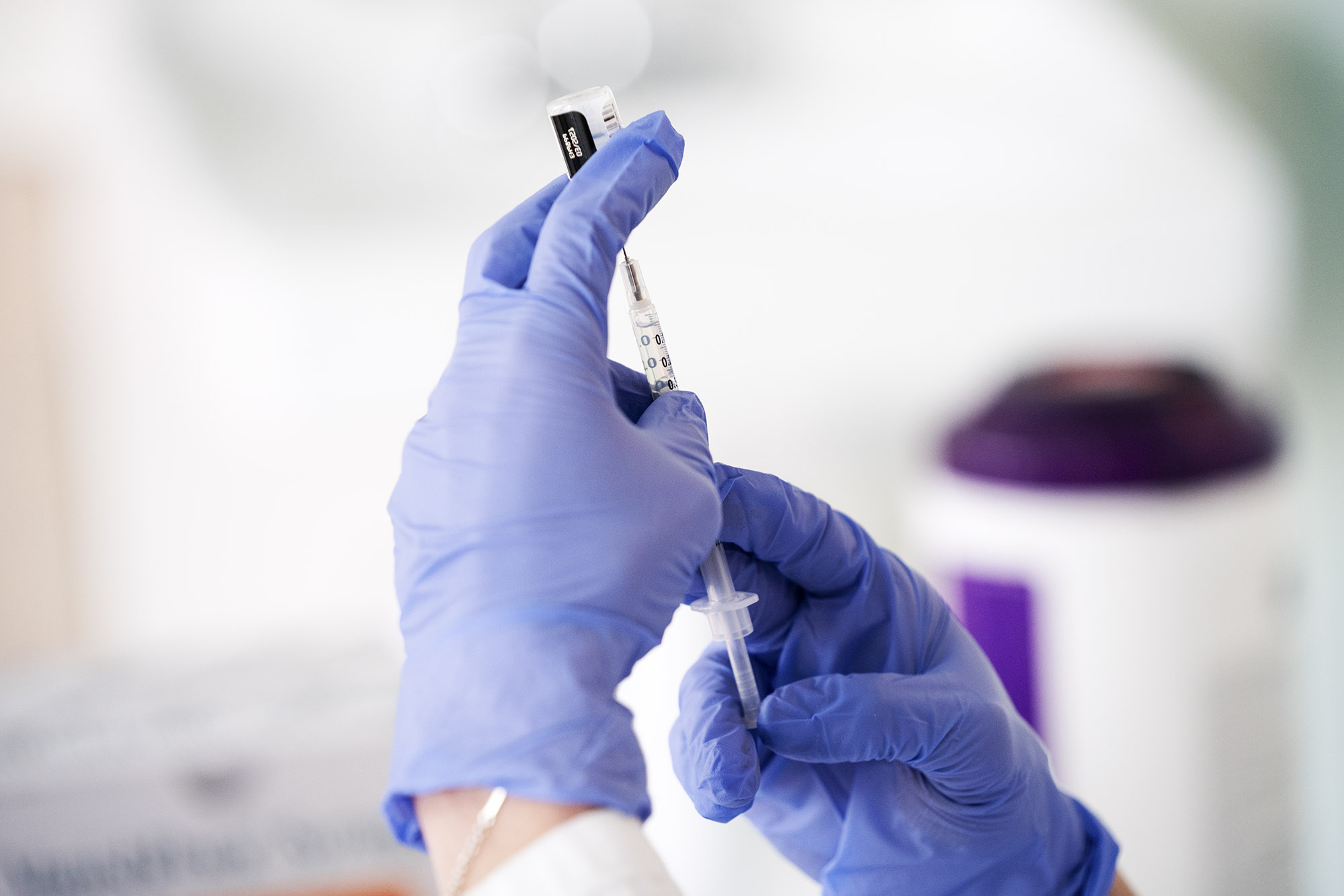 Healthcare professional drawing up a vaccine into a syringe 