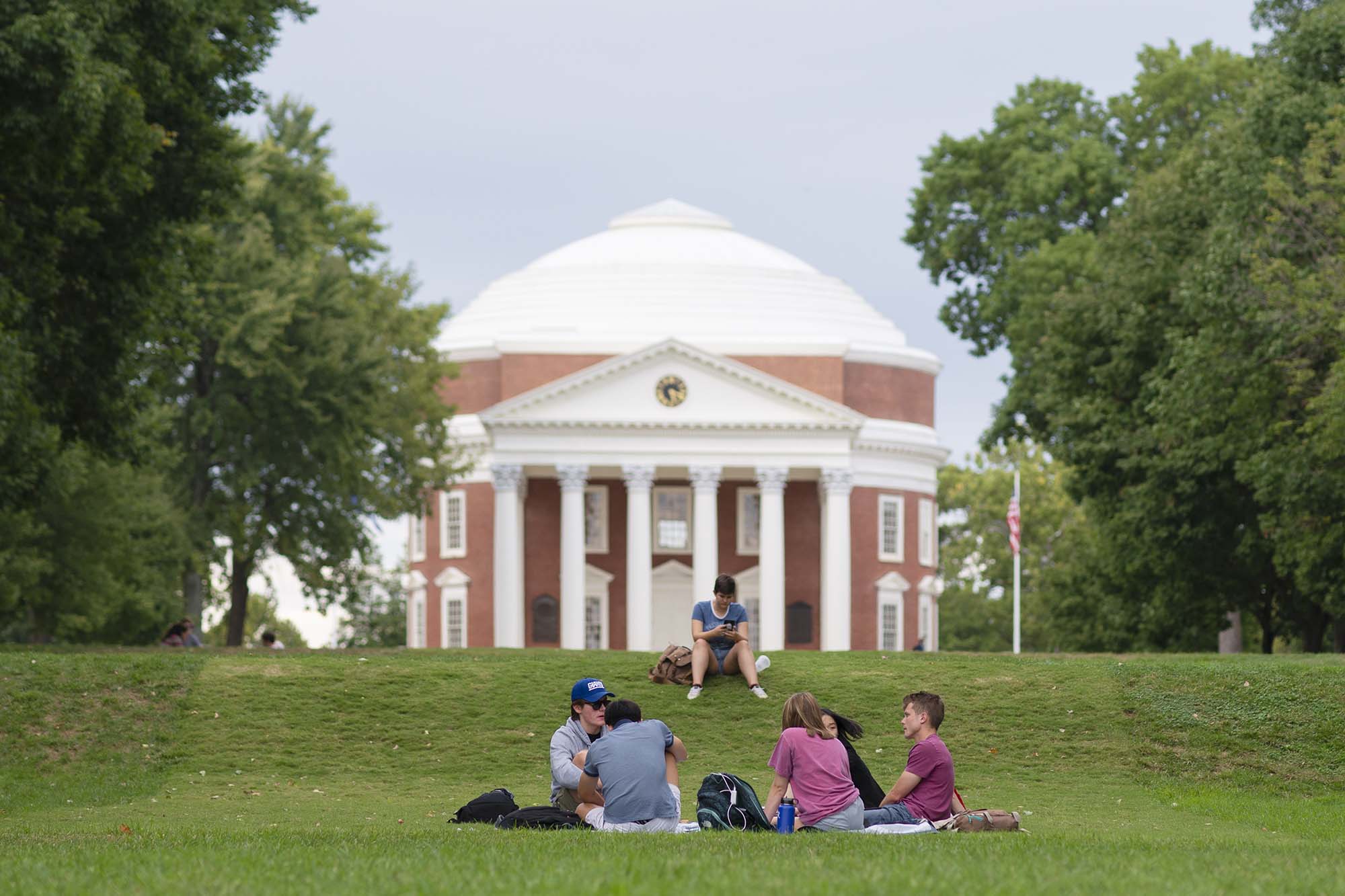 Students sitting in the grass in front of the Rotunda