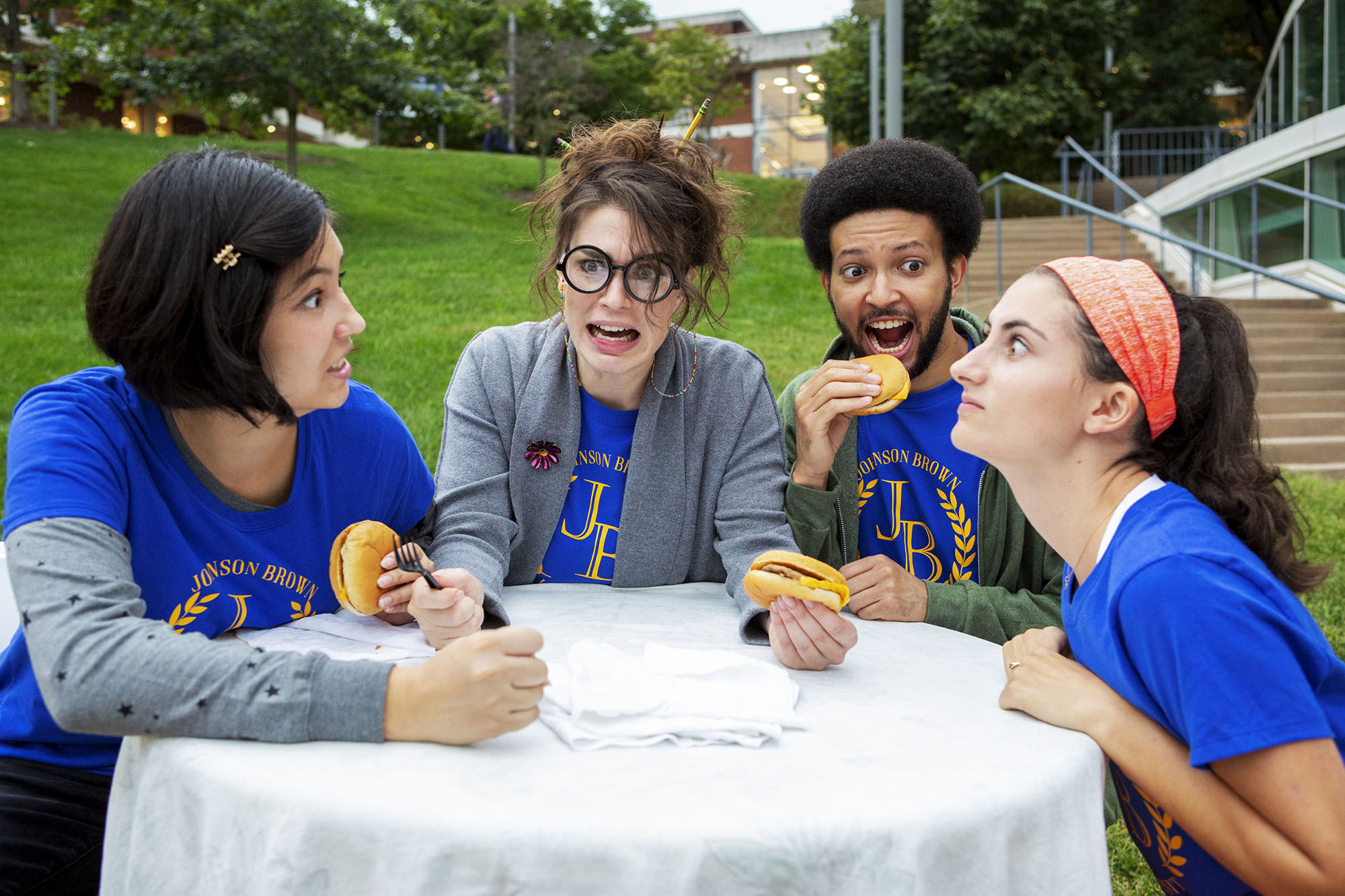 UVA drama club members sitting at a table with dramatic expressions eating cheeseburgers
