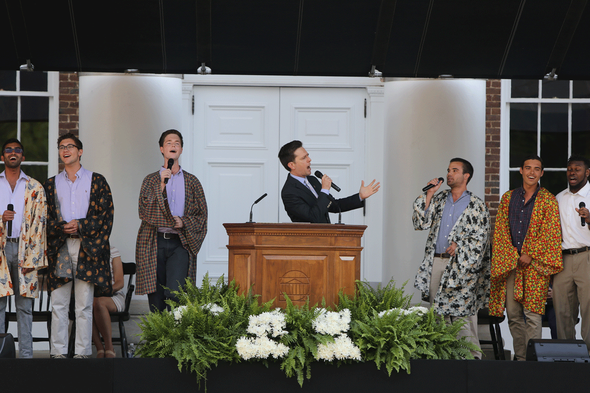 Mens a capella group signing on stage wearing various colored robes