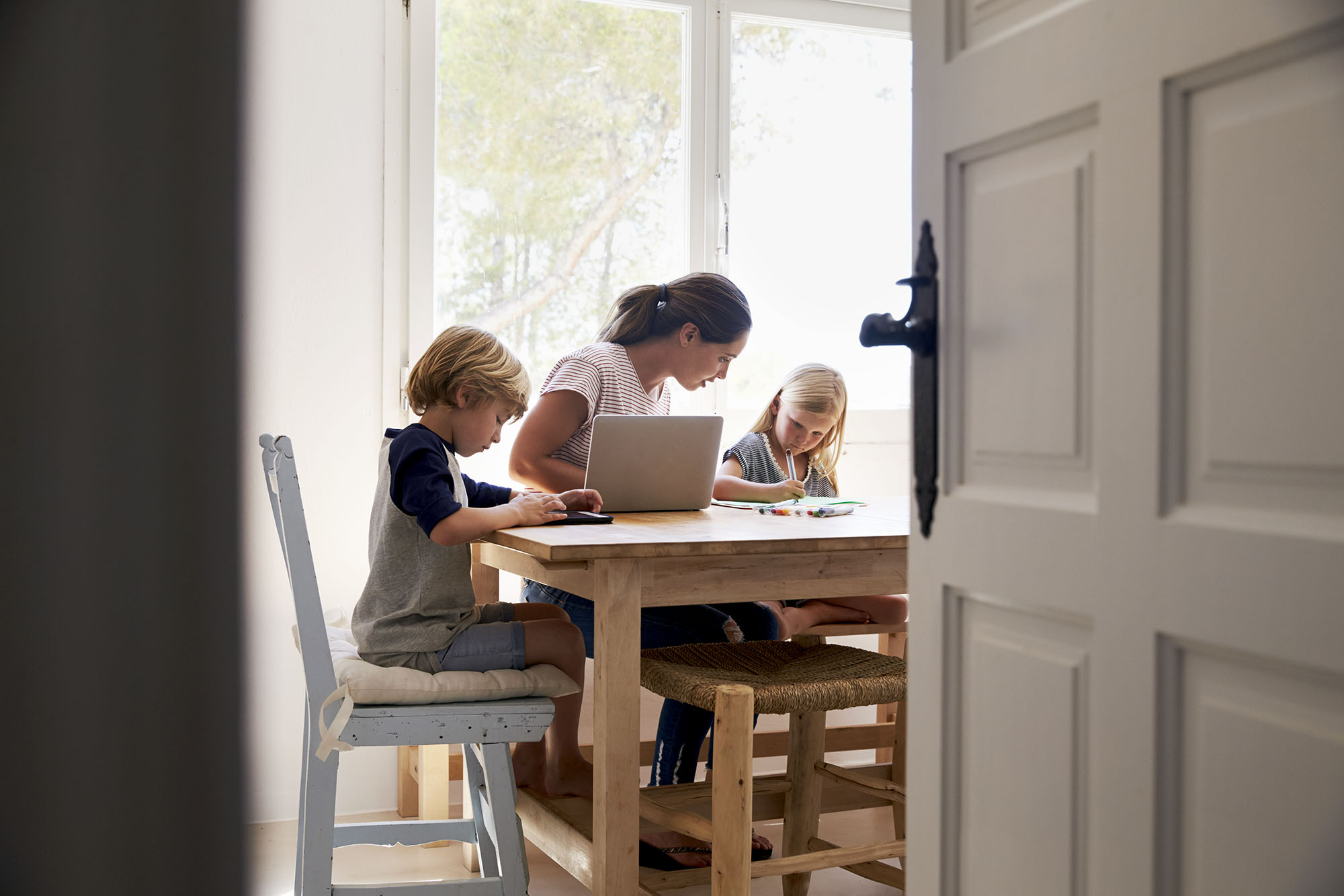 Mother working with two children at a table