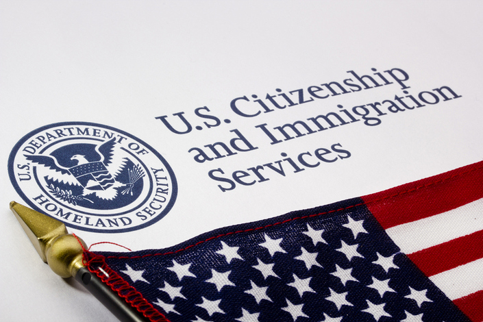 American flag next to a US Department of Homeland Security seal and text that reads. U.S. Citizenship and Immigration Services