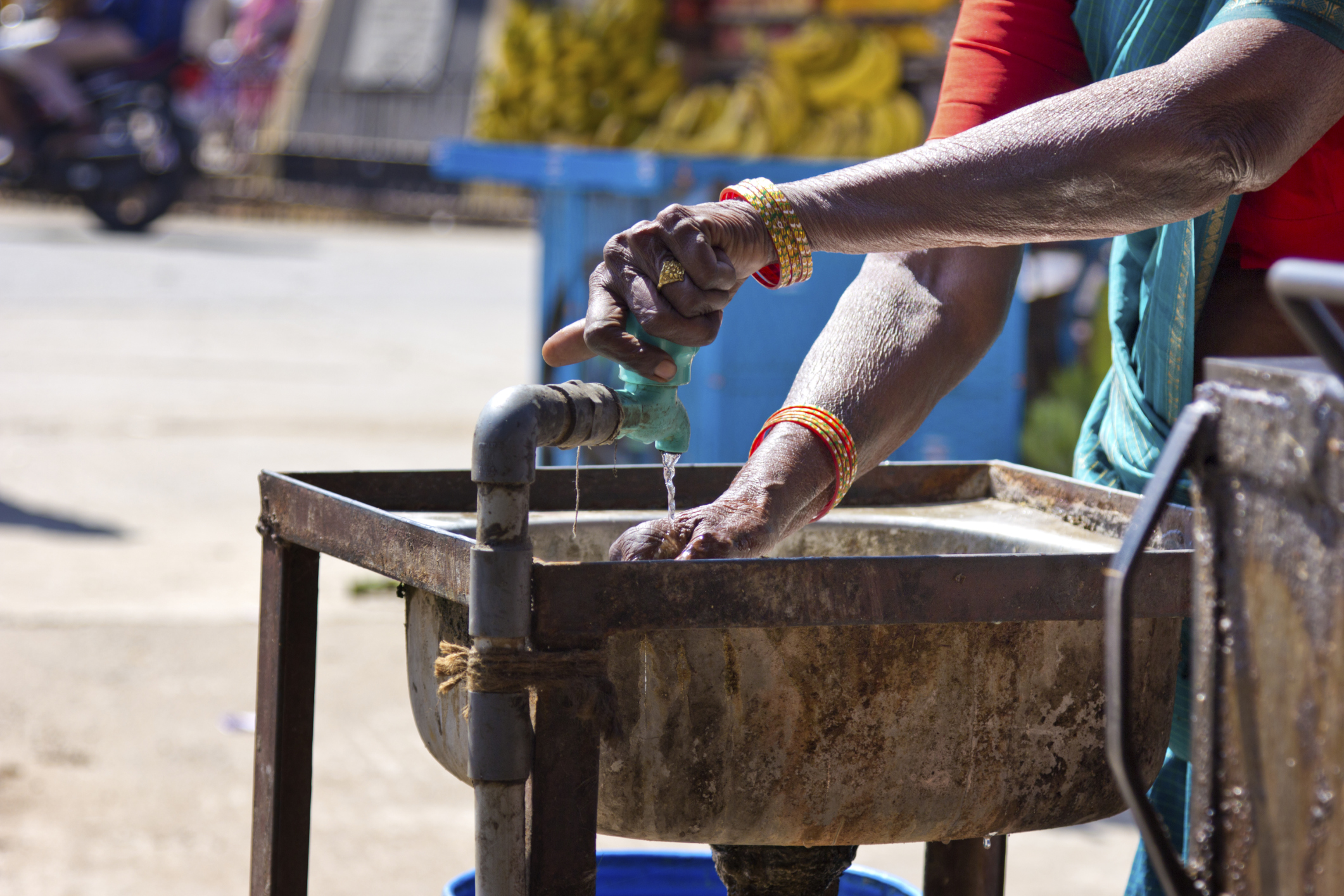 Person getting water from an outdoor sink in India