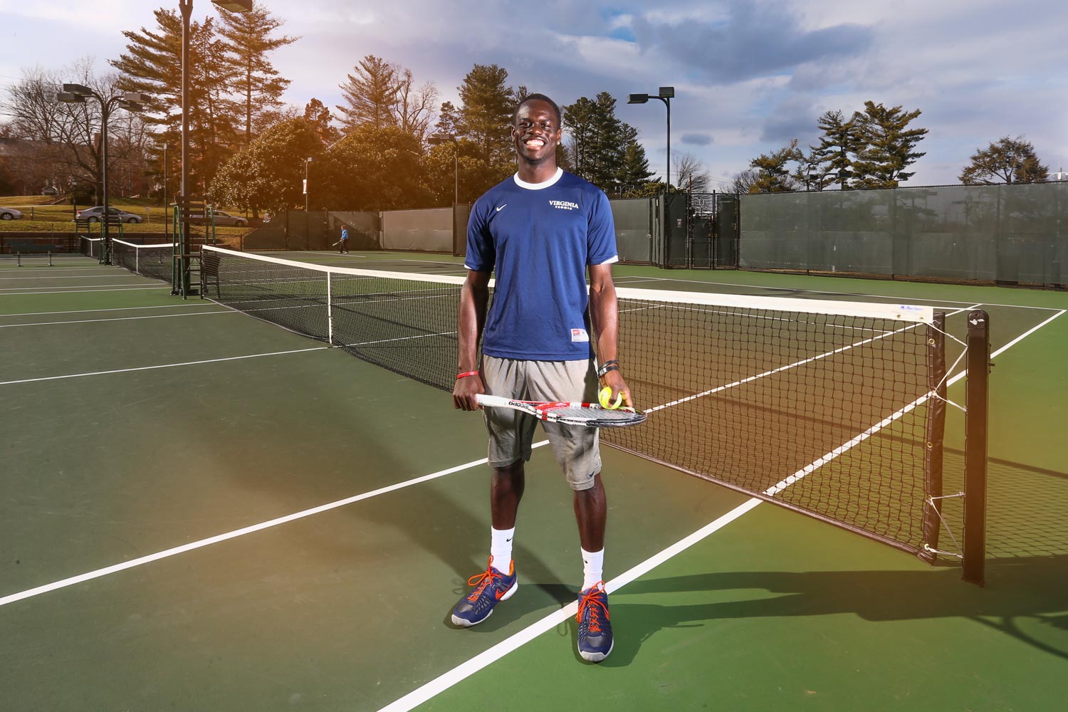 Jarmere Jenkins stands on the tennis court smiling at the camera