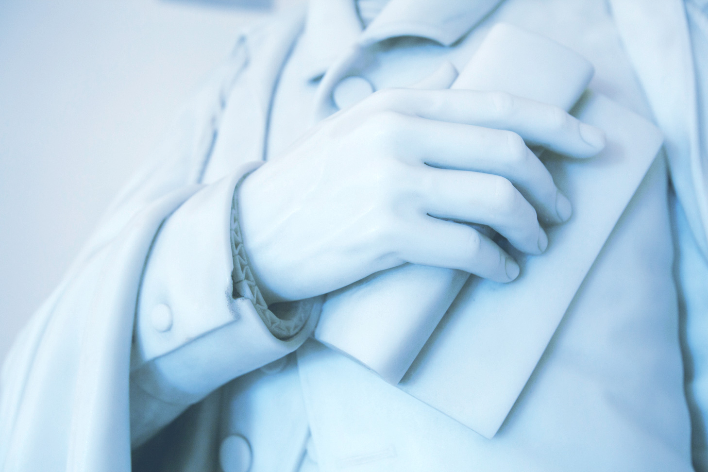 up close of a White statues hand holding something over their heart