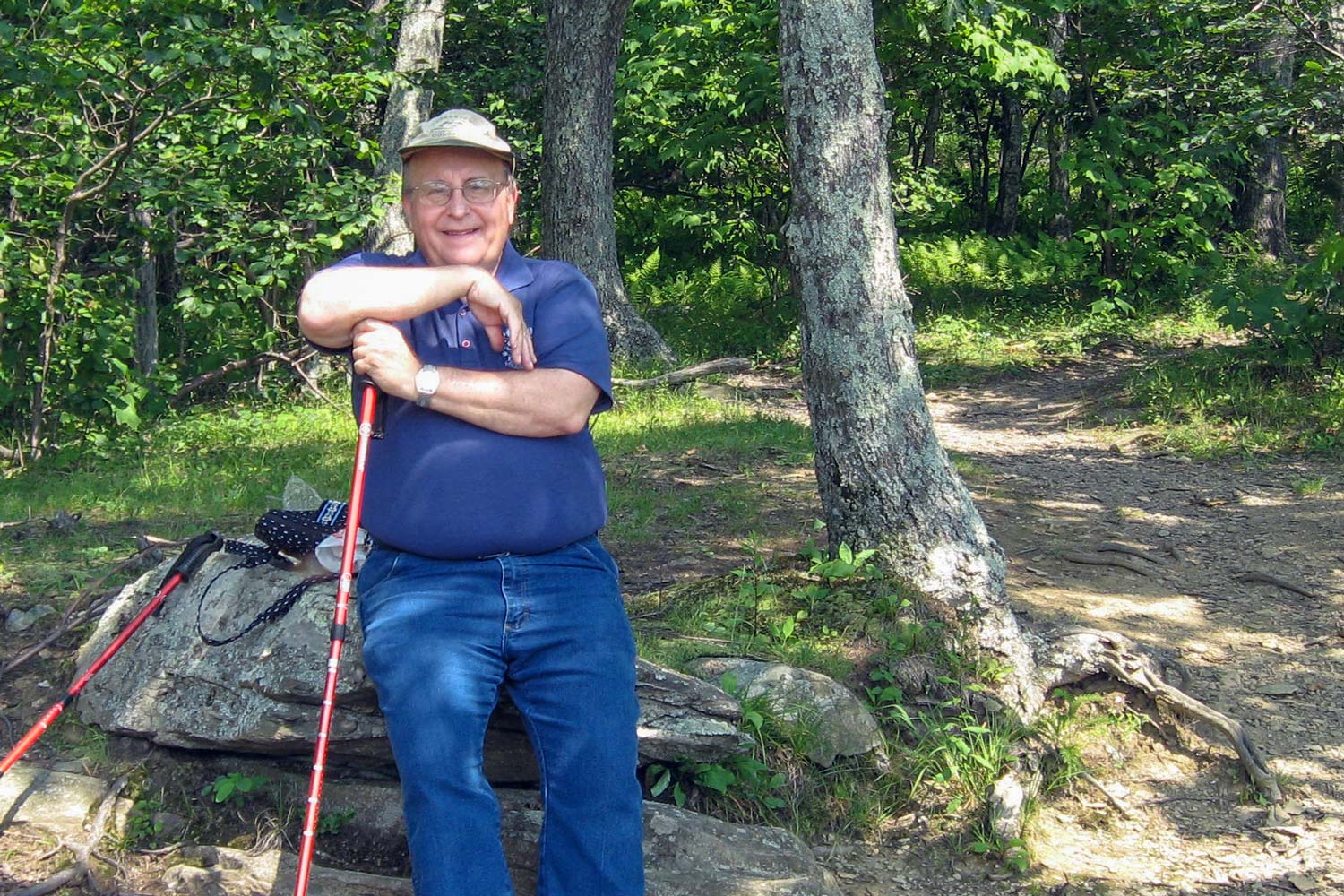 John Bonvillian resting on Rock with hiking sticks