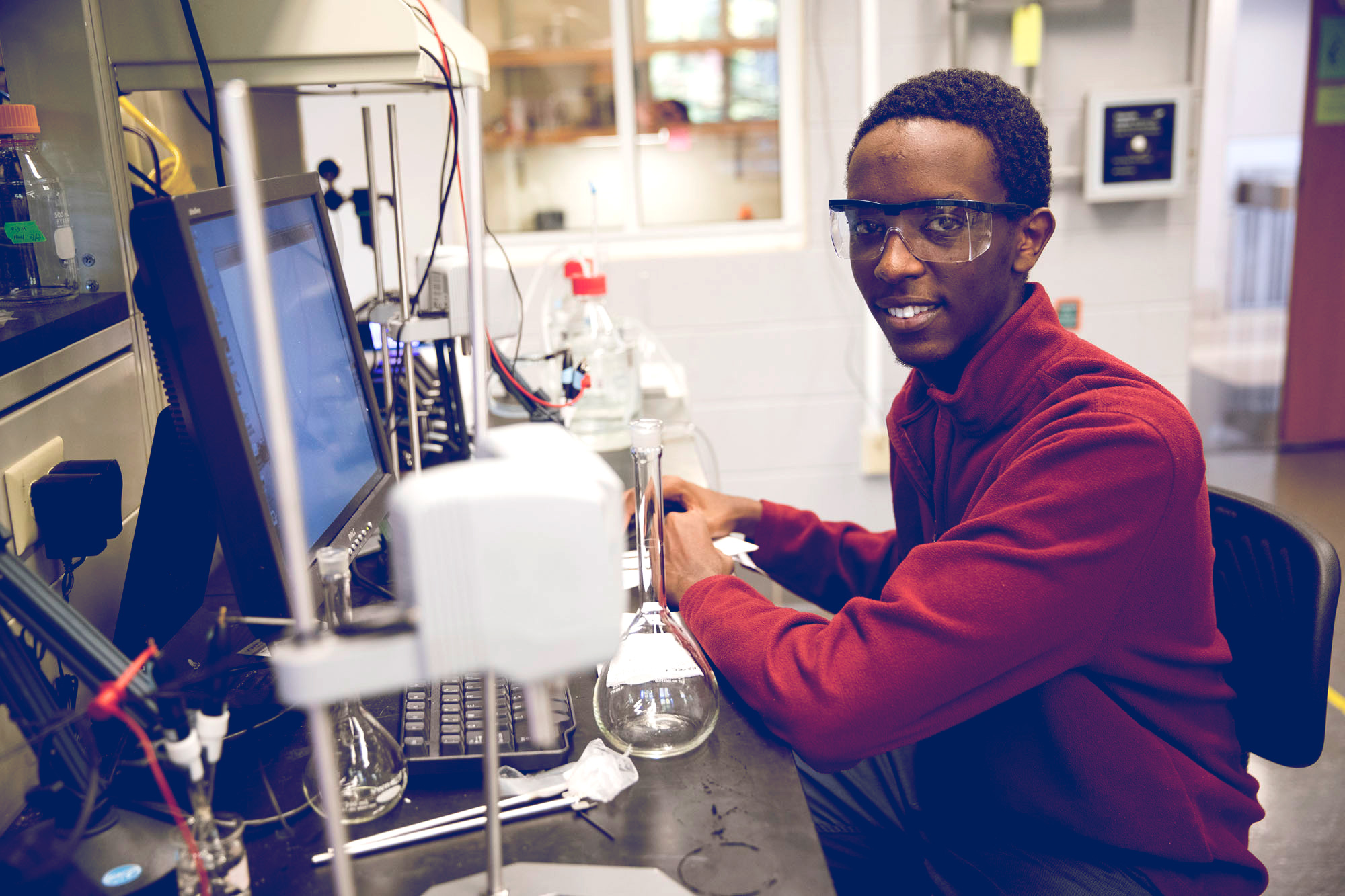 Kevin Bahati smiles at the camera in a lab