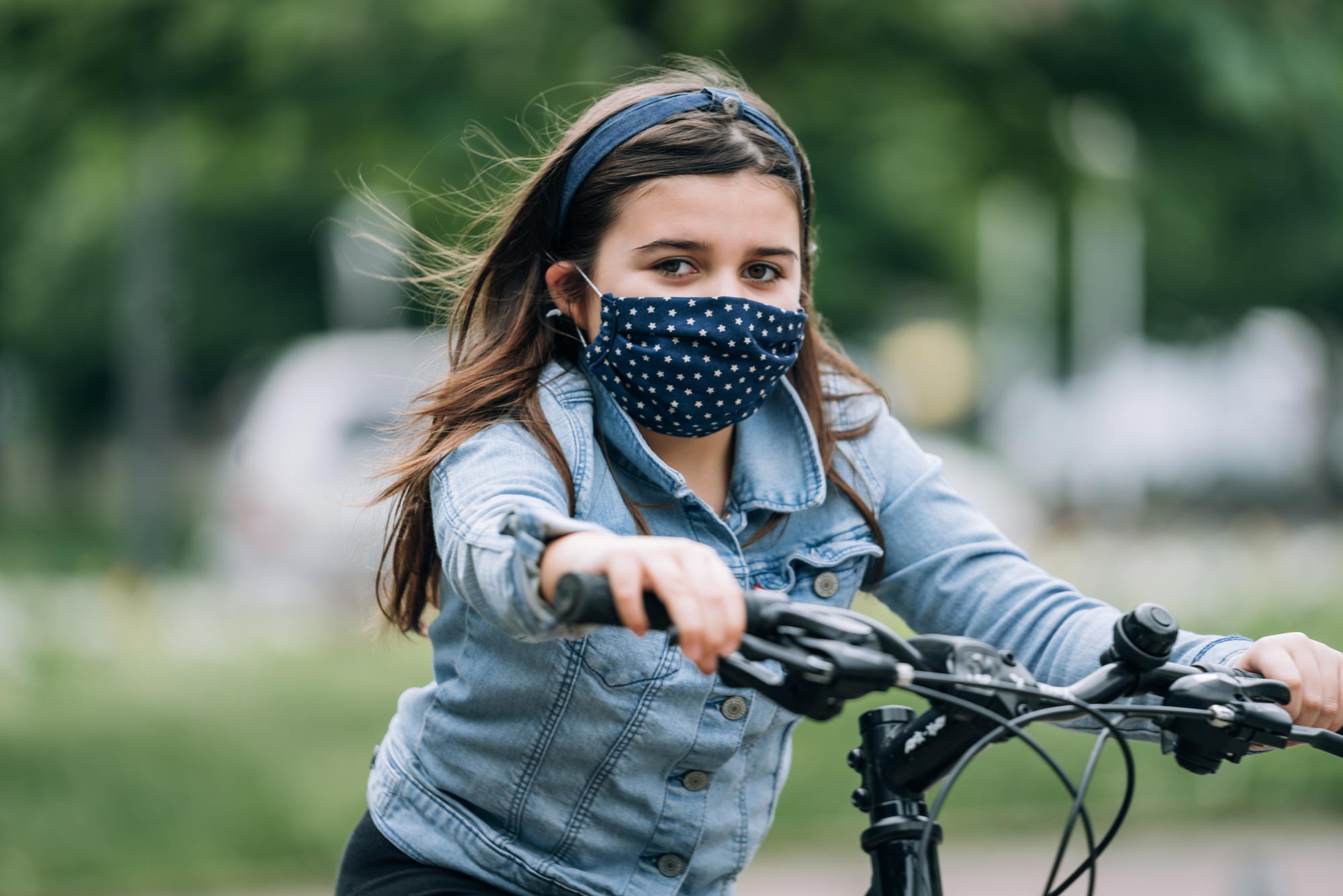 Child wearing a mask riding a bike outside