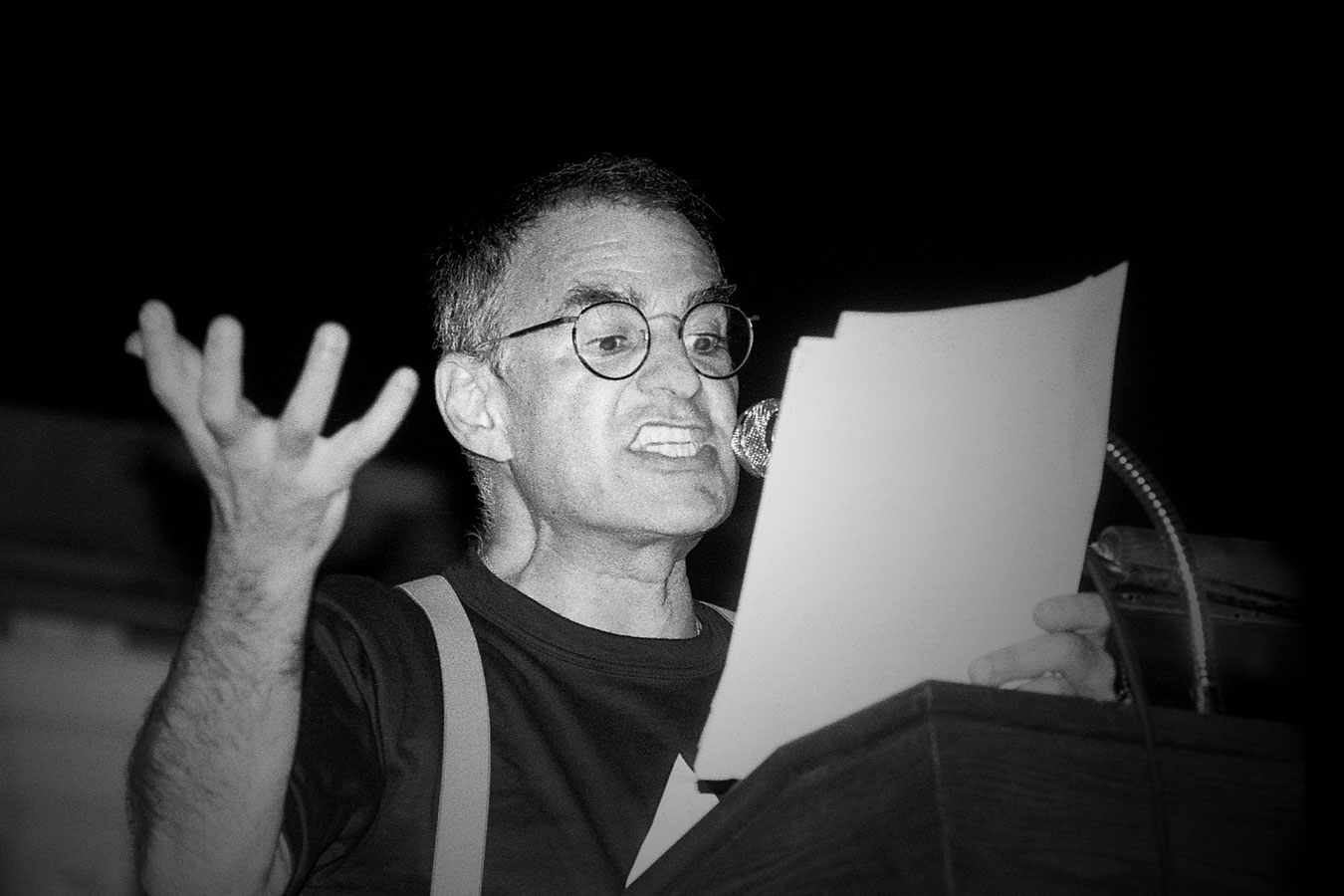 Larry Kramer reading a paper into the microphone with a very angered expression