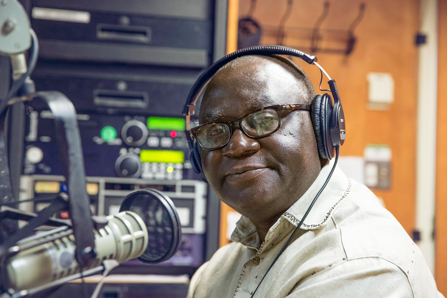 Kwesi Ghartey-Tagoe smiling at the camera in front of a microphone wearing headphones
