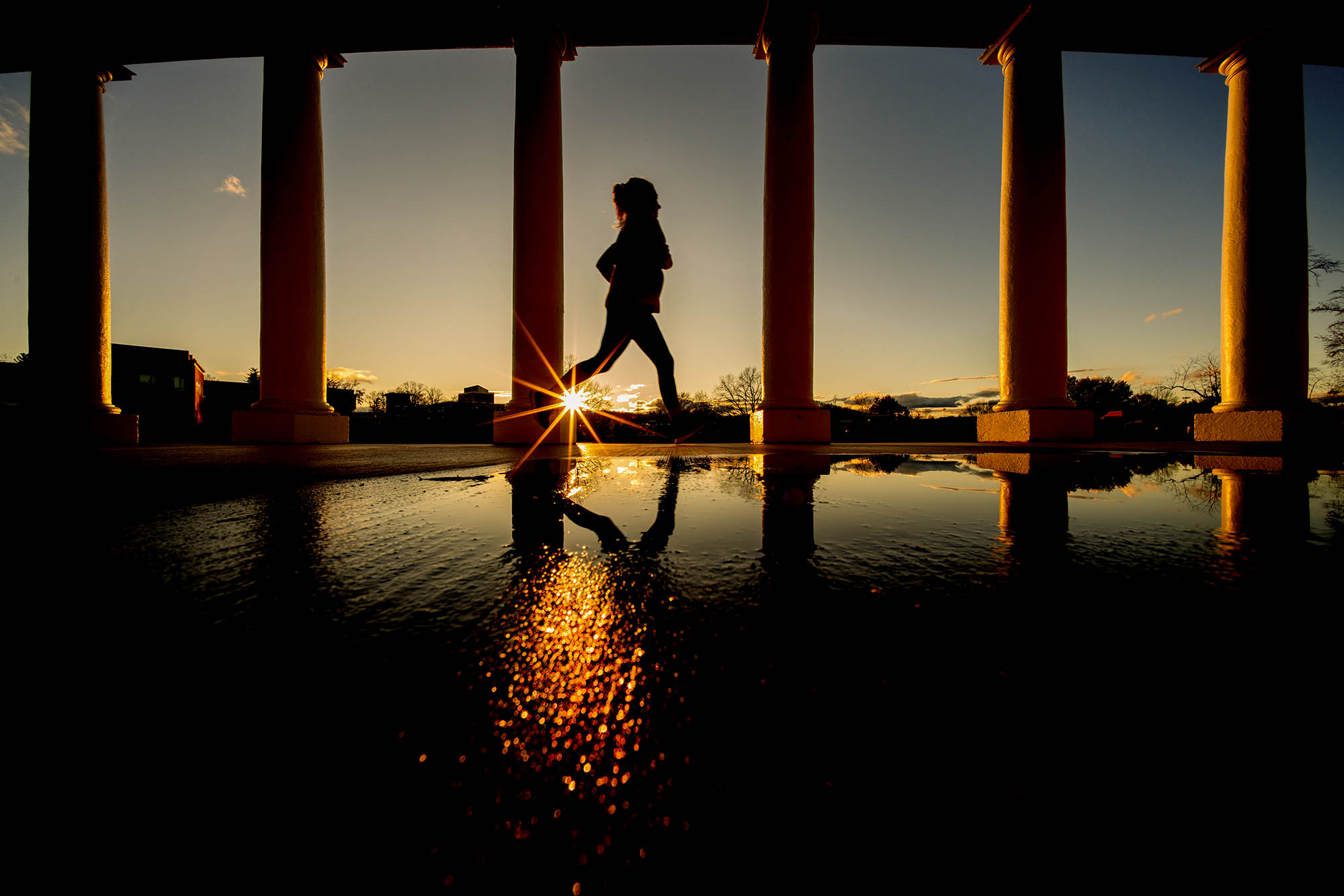 Person running at sunset through columns on grounds