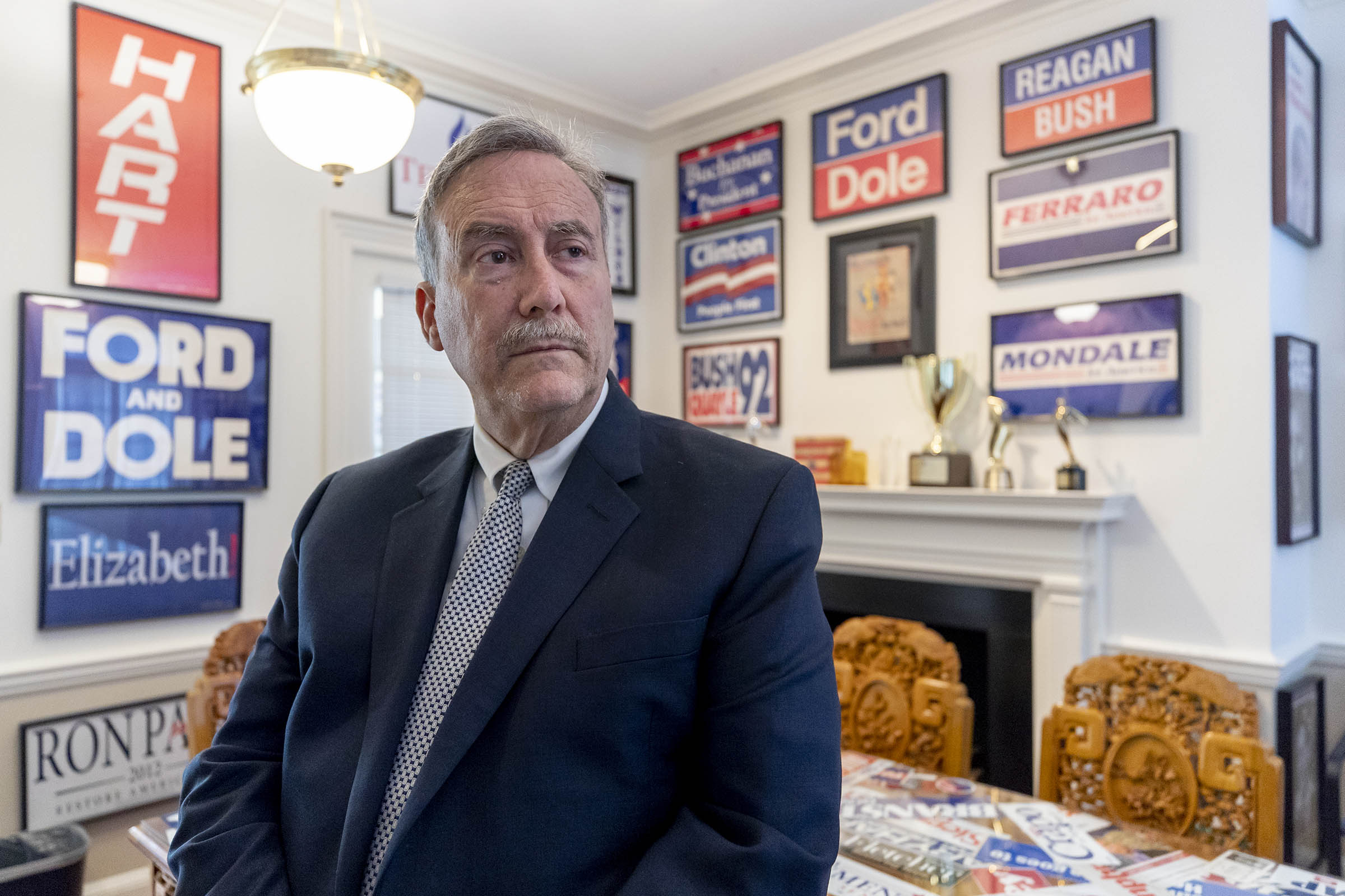 Larry Sabato stands at a table looking to the right of the camera