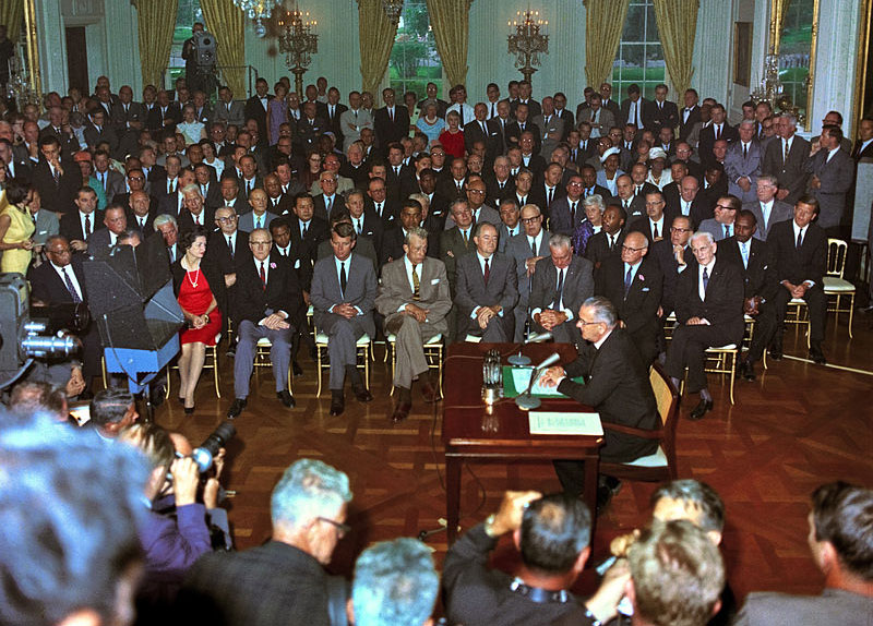 Lyndon B. Johnson signs the Civil Rights Act surrounded by people